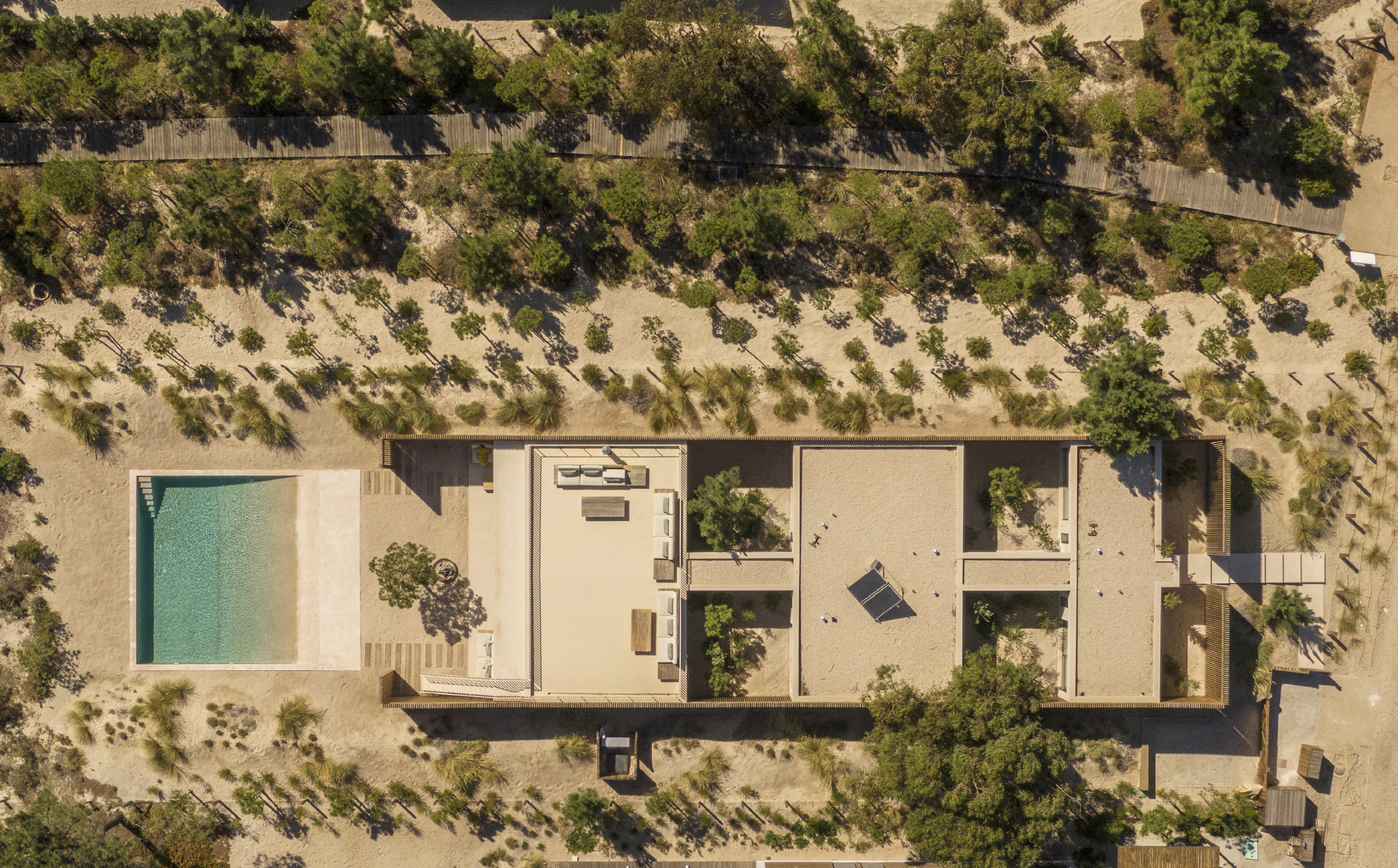 Aerial view of the linear residence with central courtyard pool surrounded by sandy terrain and scattered pines