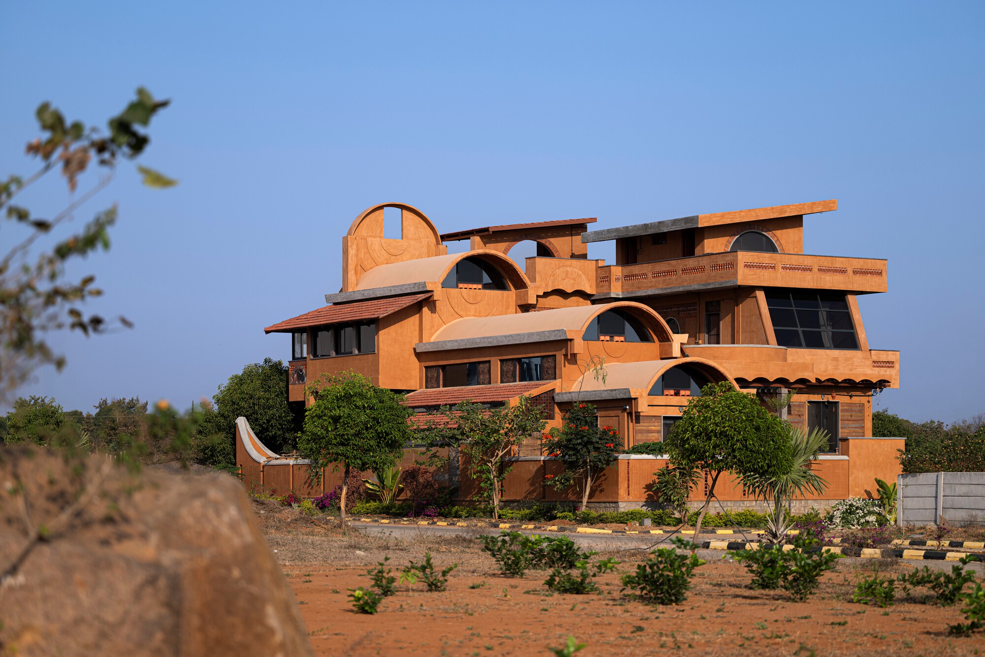Full building view from a planted field showing the stacked arched forms at dusk