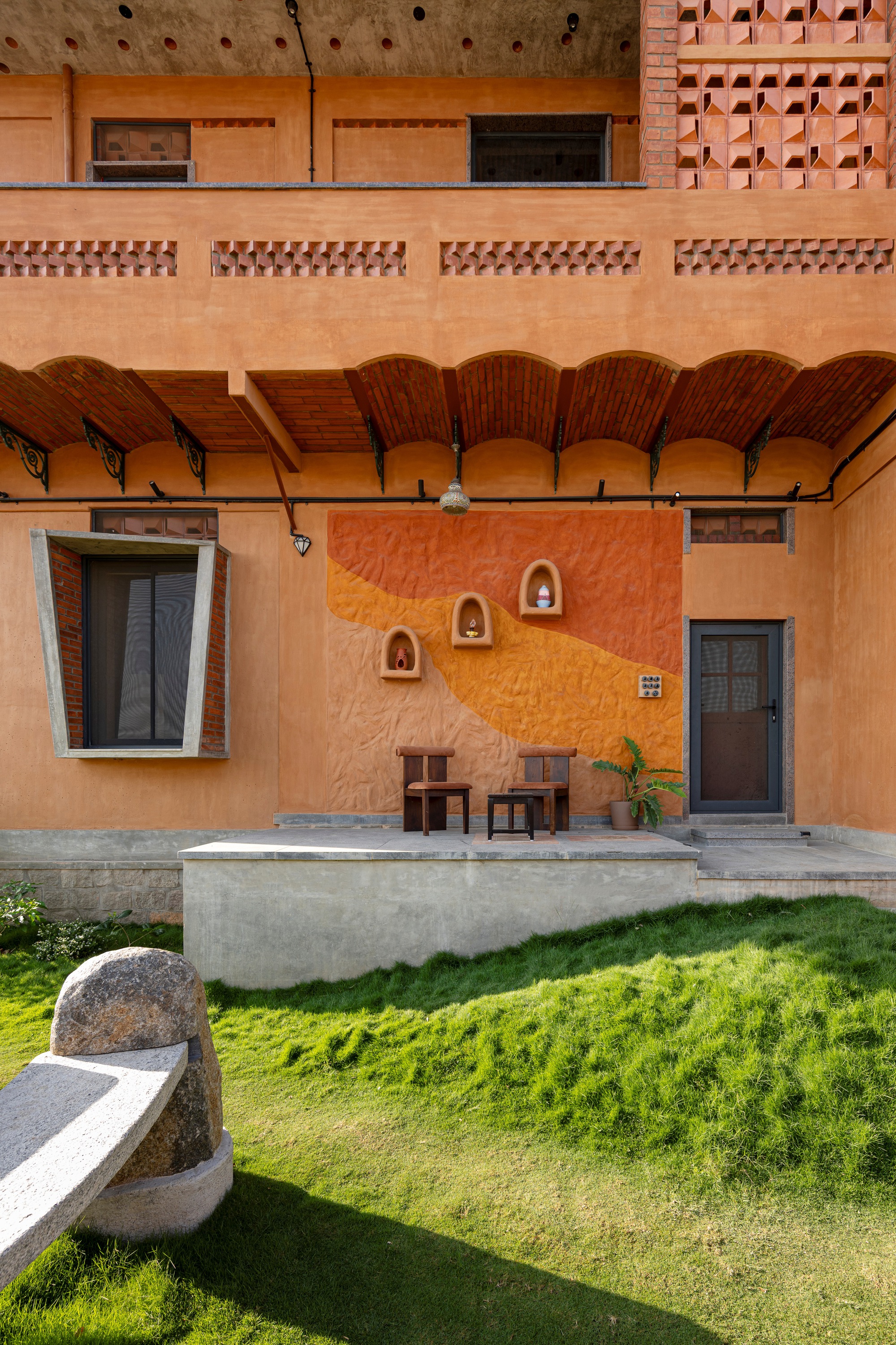 Covered terrace with exposed brick vaulted ceiling, niche wall ornaments, and lawn below