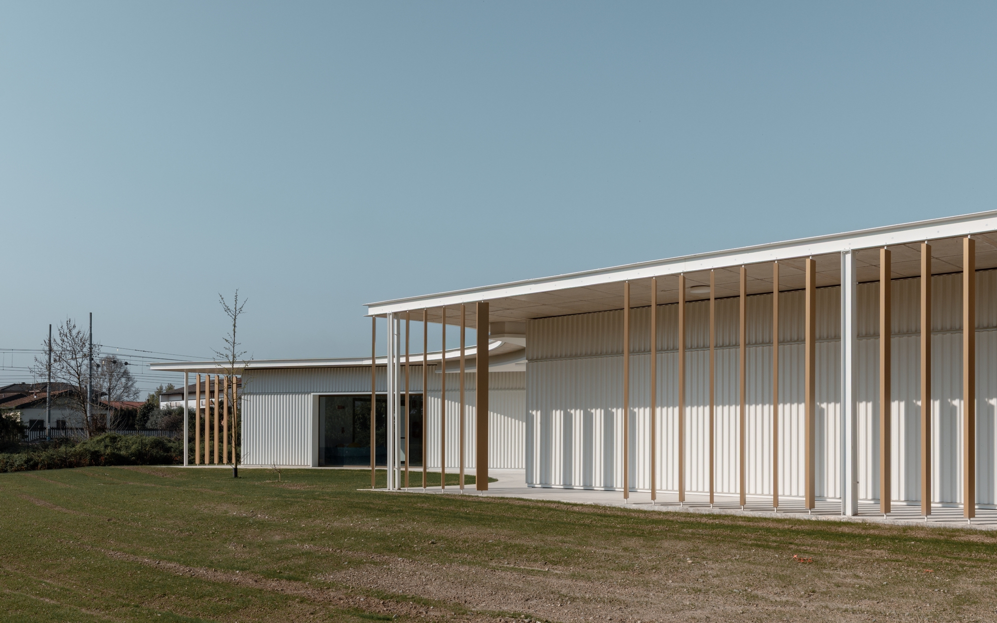 Exterior view of timber colonnade with vertical white metal cladding under an overcast sky