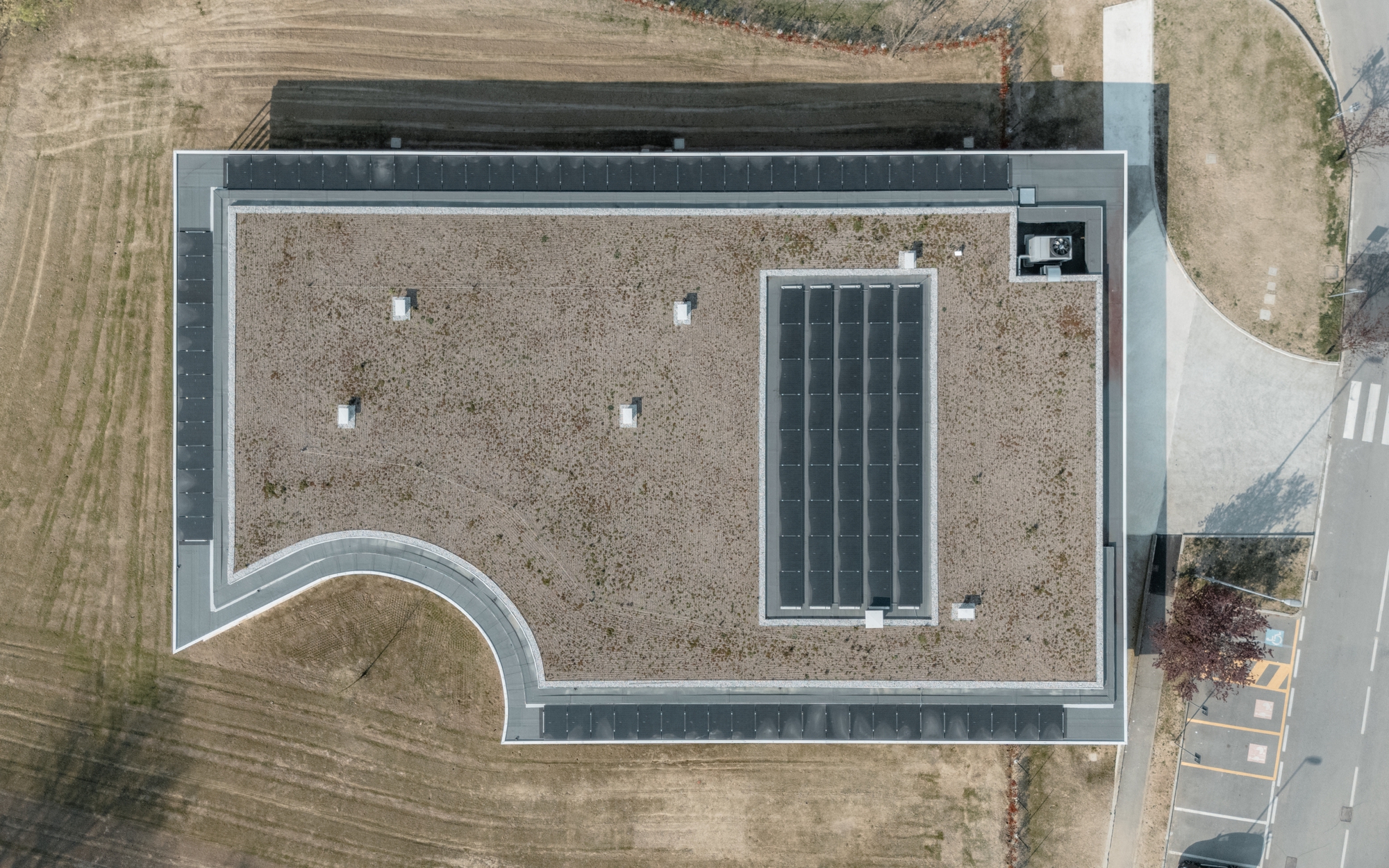 Aerial view of the gravel roof with four skylights and a rectangular solar panel array