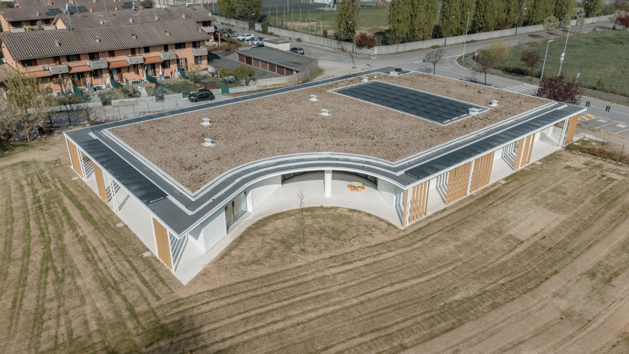 Aerial view of the gravel and solar panel roof with curved corner and surrounding agricultural fields