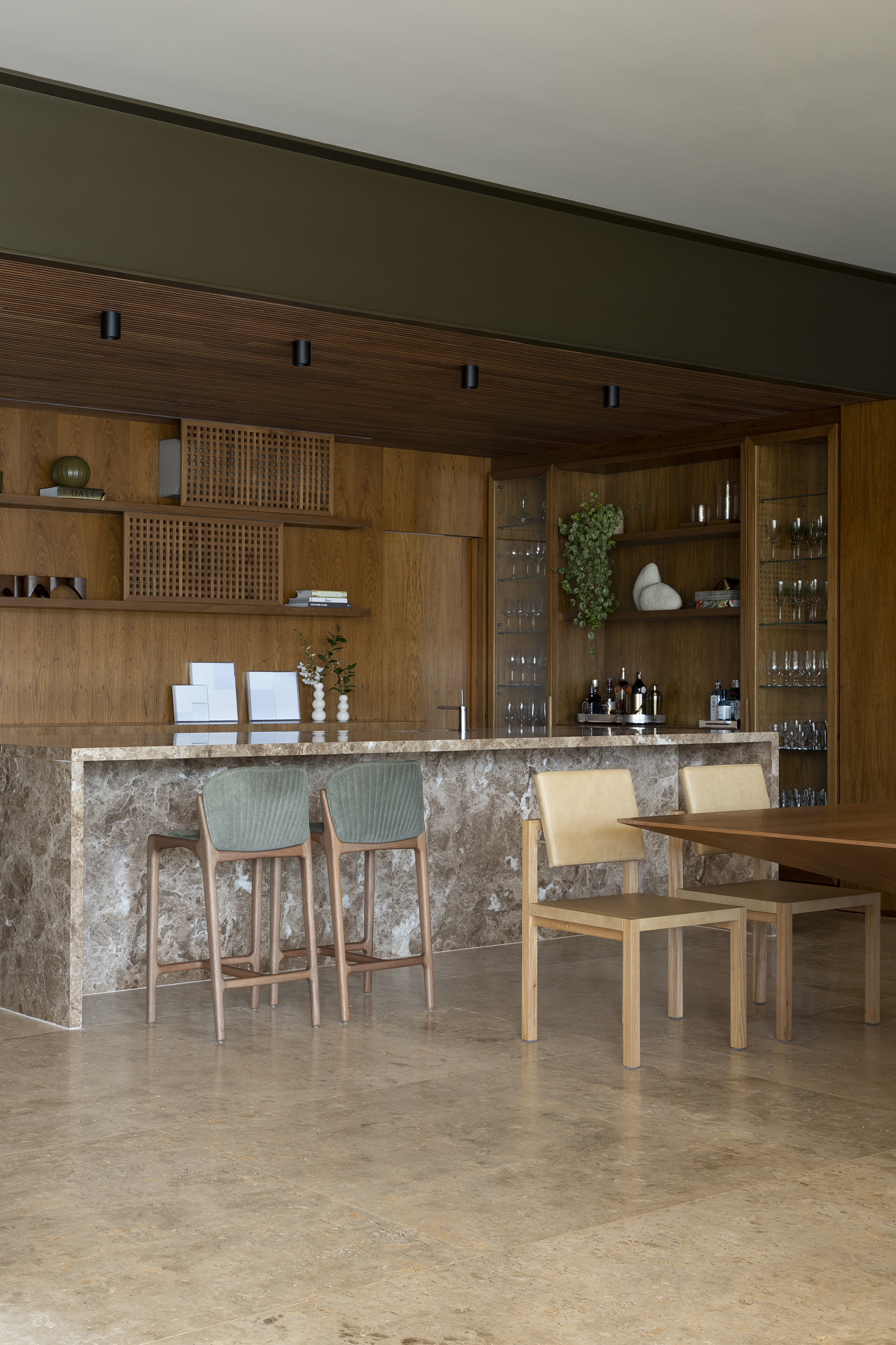 Kitchen bar with textured stone counter, timber cabinetry, and pendant lighting above dining seating
