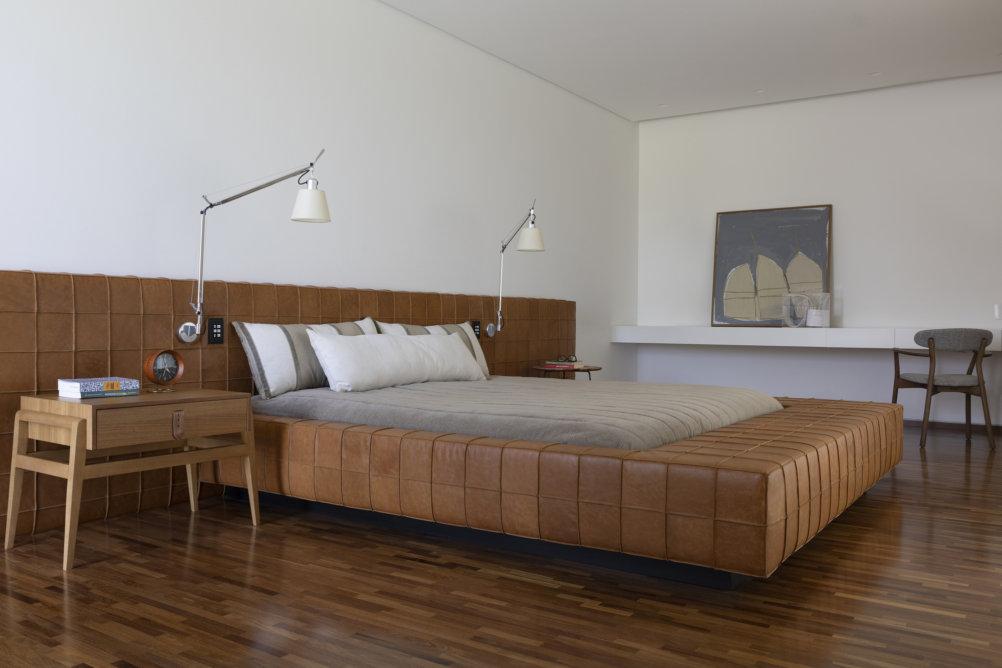 Bedroom featuring a quilted leather headboard and platform bed on dark timber flooring