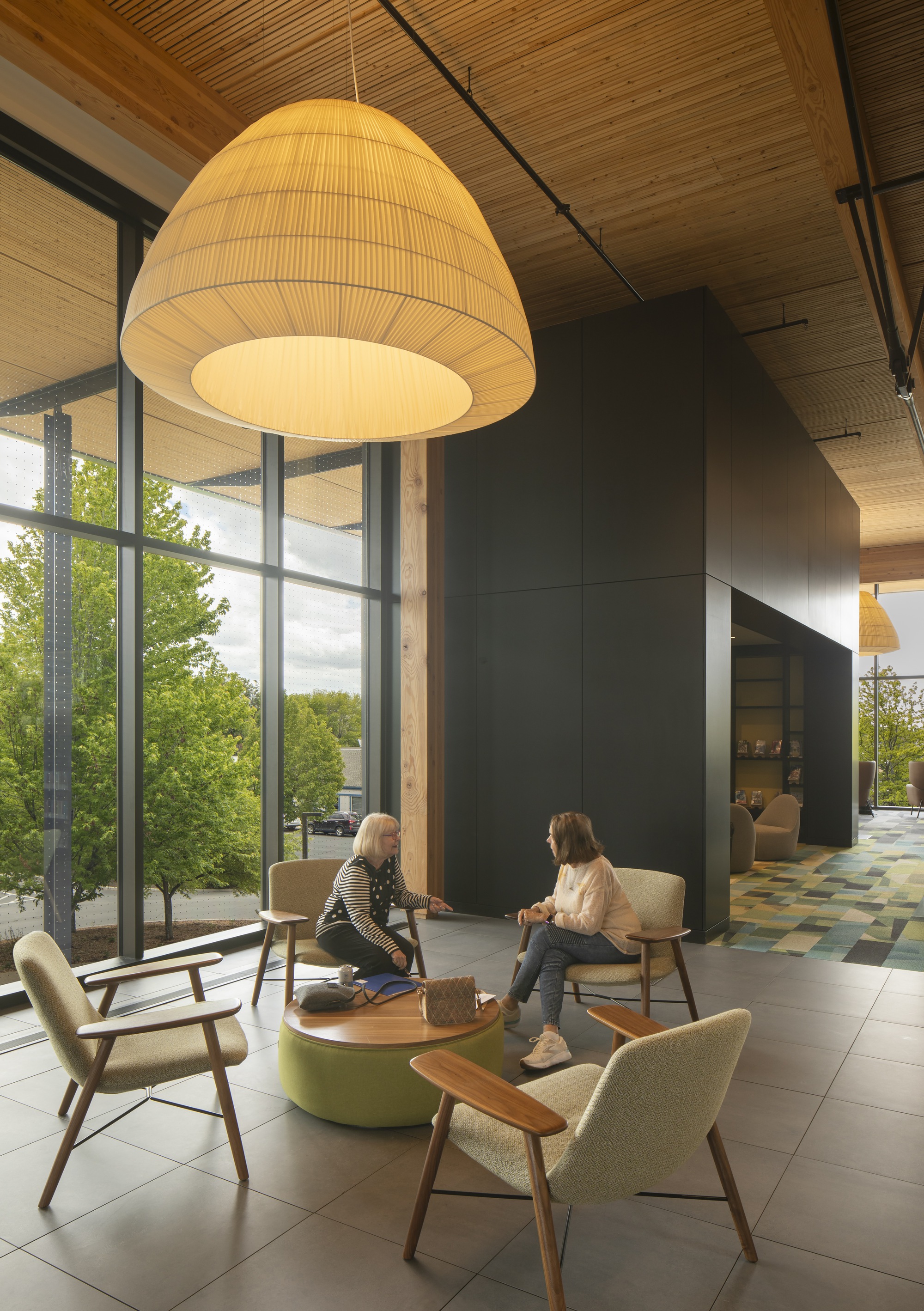 Seating alcove with oversized pendant fixture, lounge chairs, and window overlooking trees outdoors