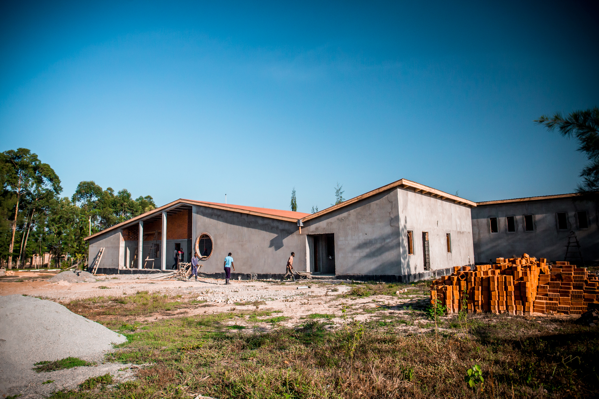 Side view of the concrete block volumes with terracotta roof tiles and stacks of bricks