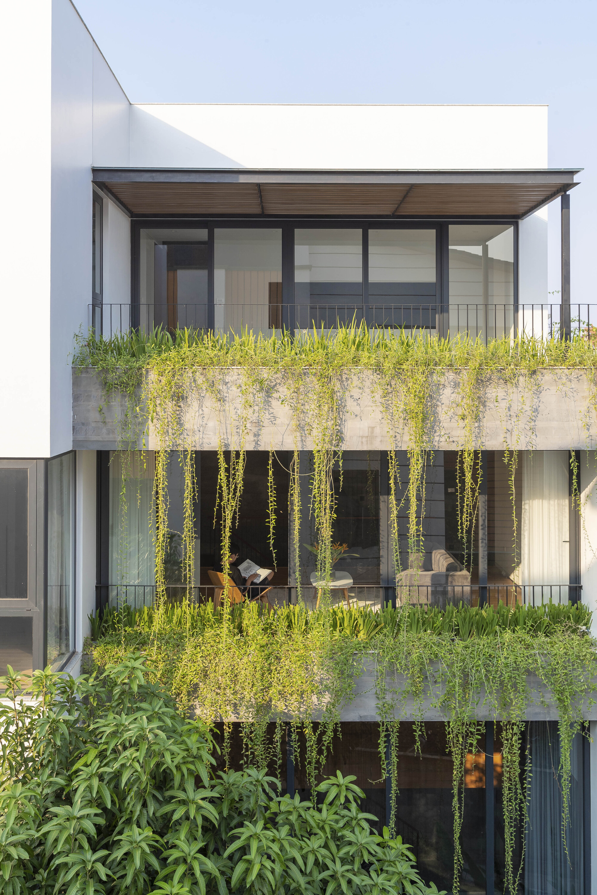 Garden facade with stacked concrete planters and cascading greenery spilling over multiple levels