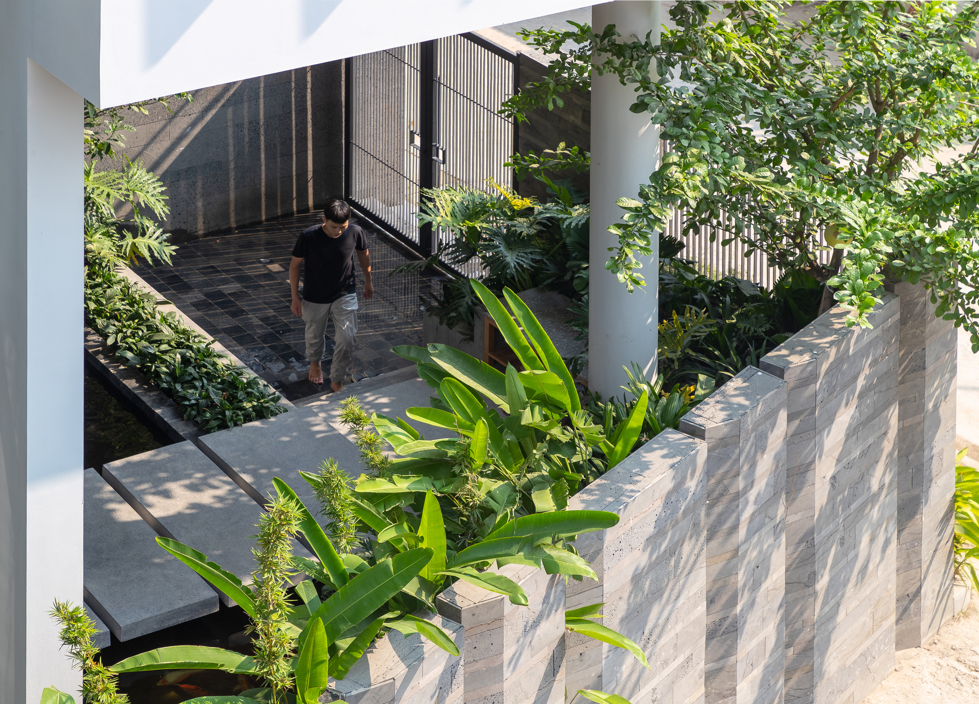 Elevated walkway with steel railings connecting planted terraces as a figure descends