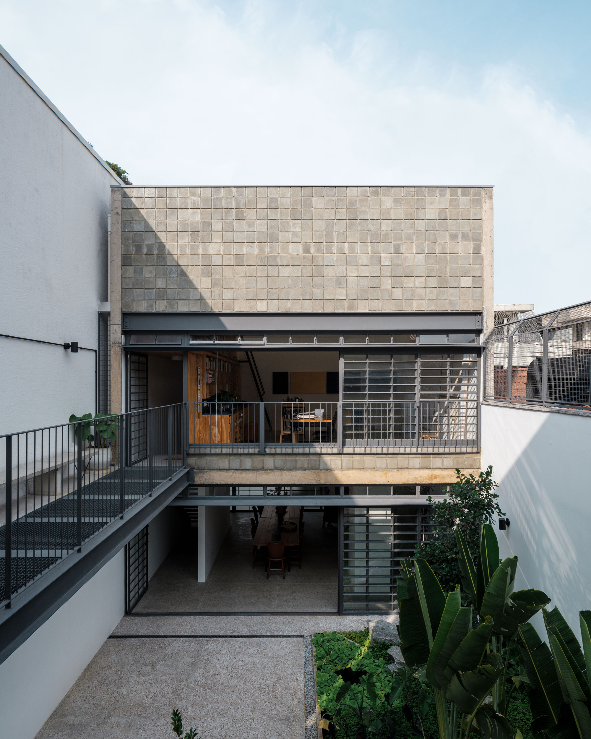 Courtyard elevation showing two-story concrete volume with beige ceramic tile facade and concrete terrace balconies