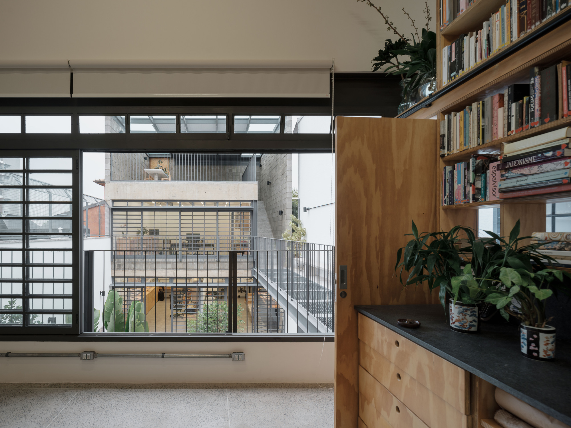 View through gridded window to interior courtyard with stairs, railings, and planted bed with banana palms