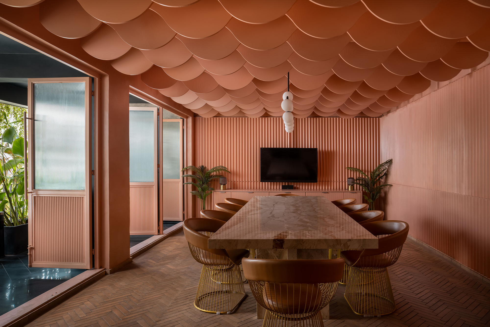 Conference room with scalloped terracotta ceiling panels, vertical ribbed wall cladding, and a timber table