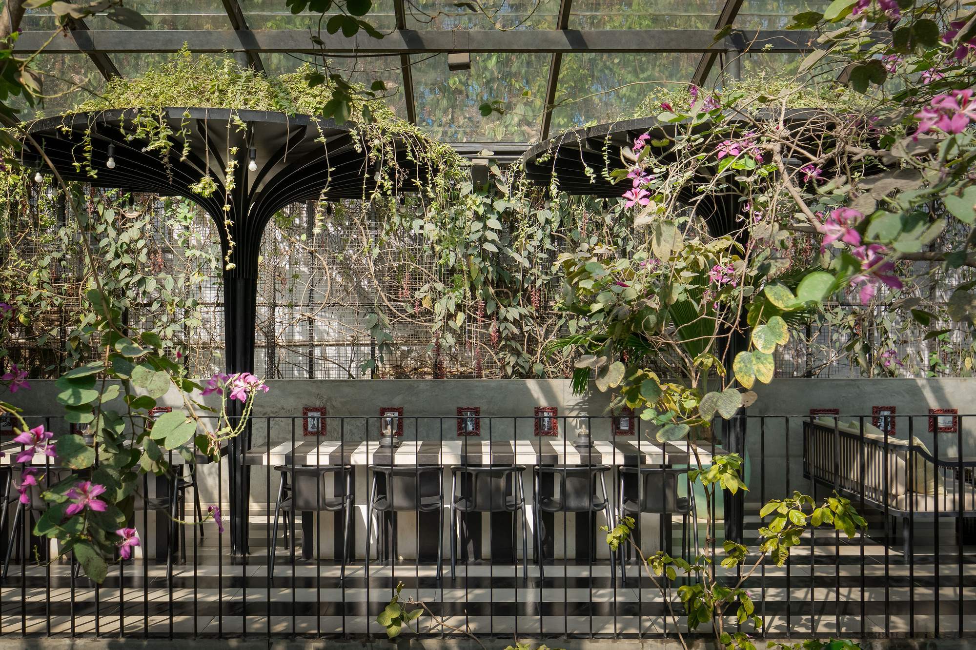 Upper level dining counter backed by a planted wall with flowering vines and glass enclosure