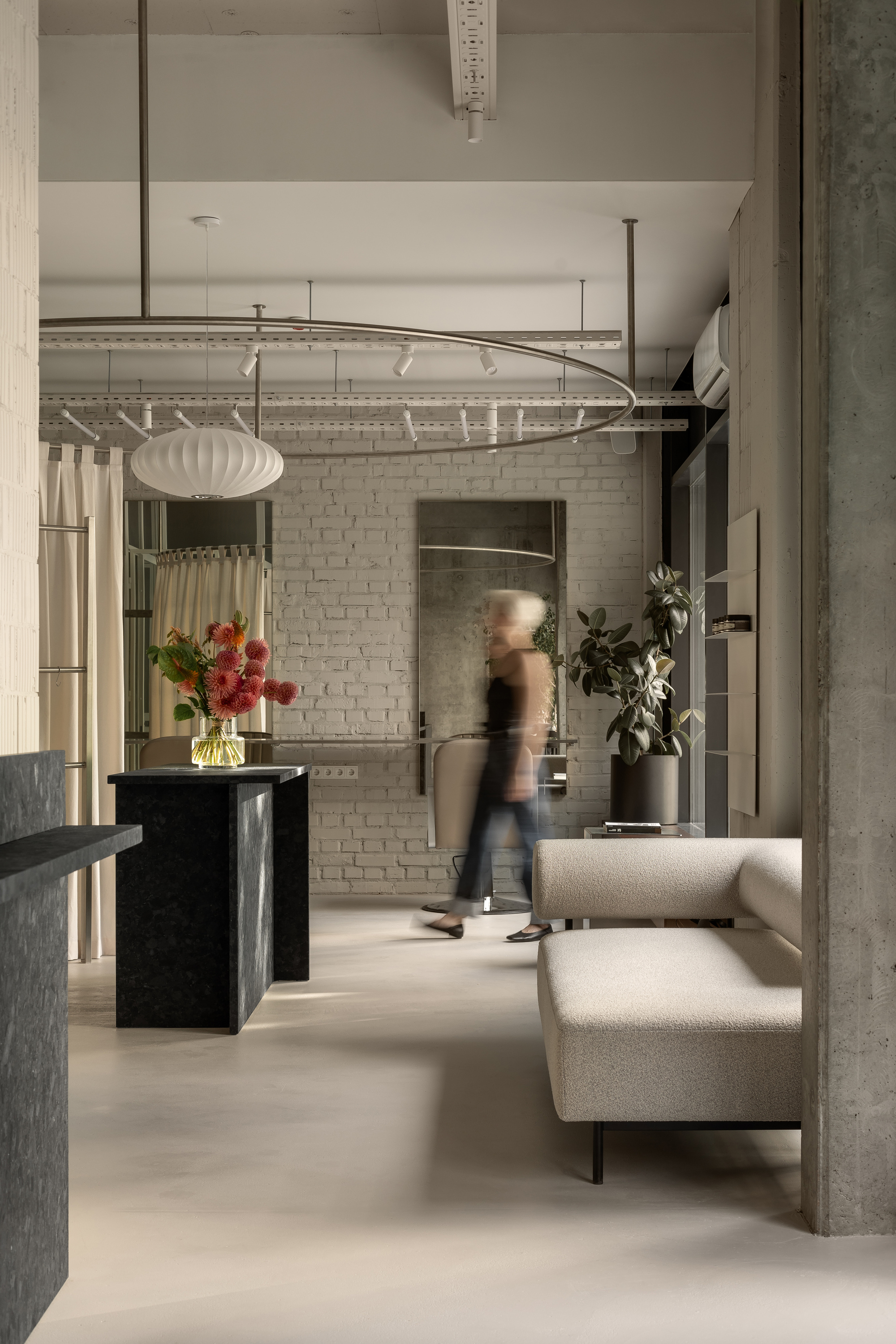 Open interior with white brick wall and figure walking past dark stone counter and seating