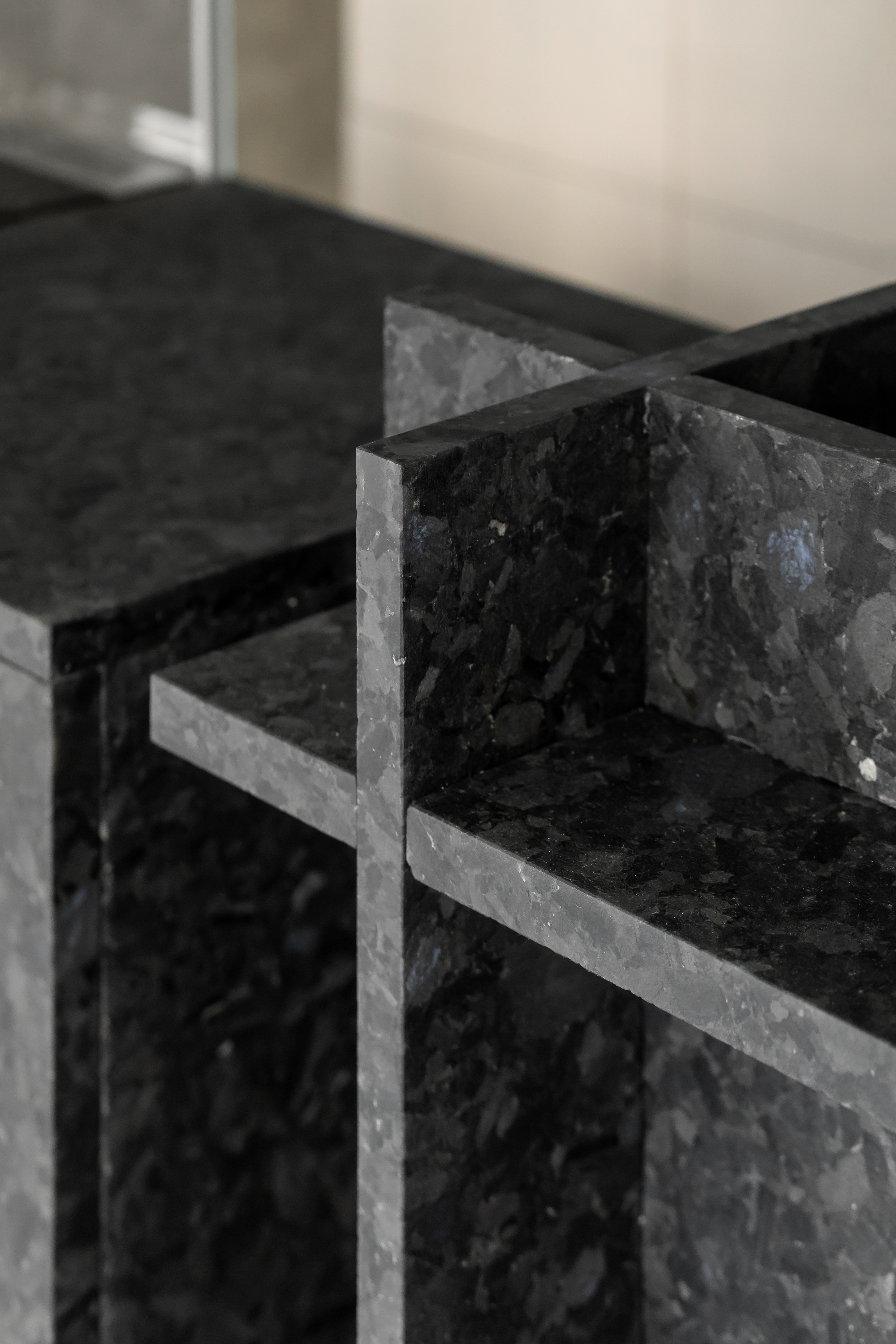 Detail of black terrazzo stone shelving with mitred corner joints and visible aggregate