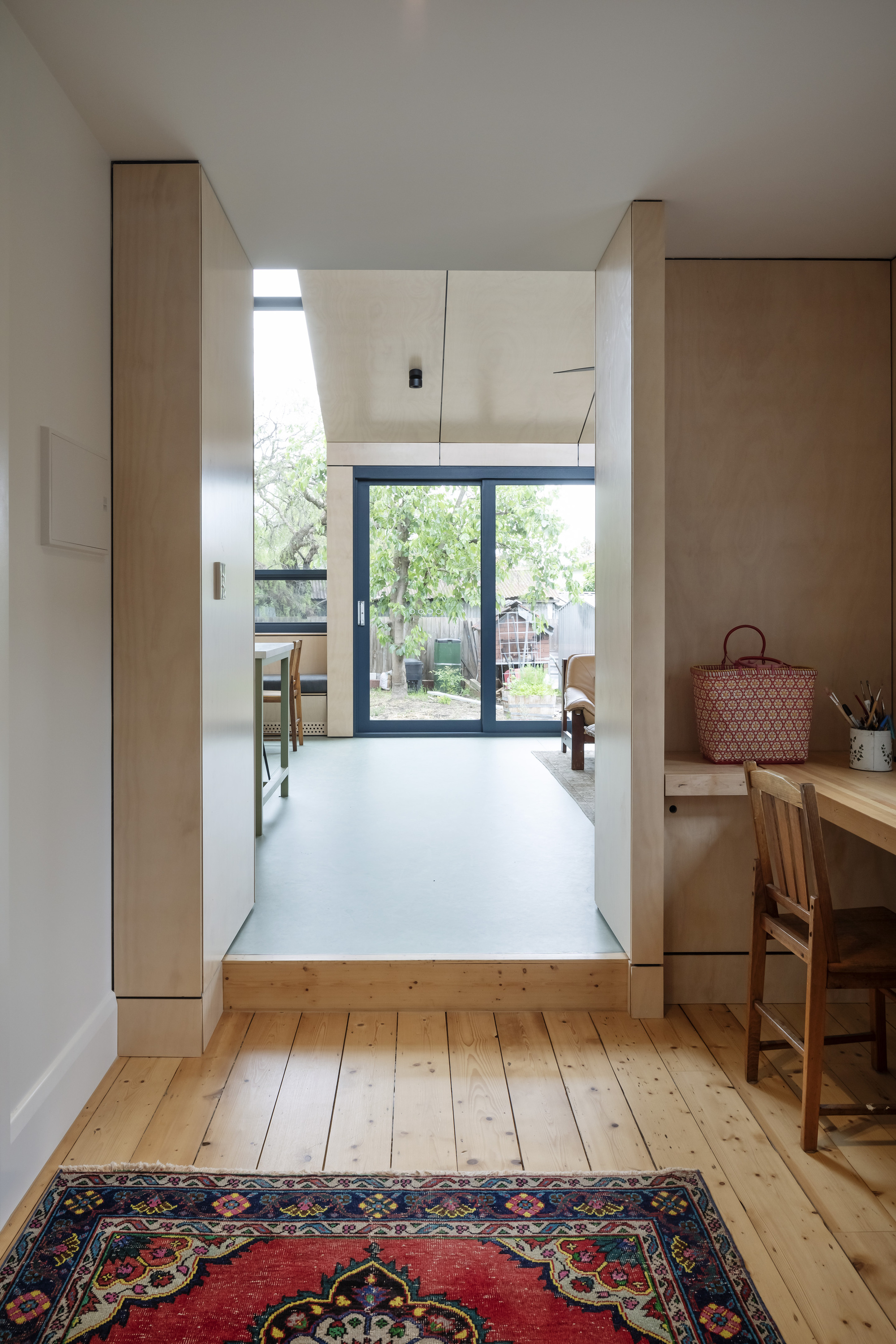 Interior view through timber-framed doorway to kitchen and glazed doors opening onto garden