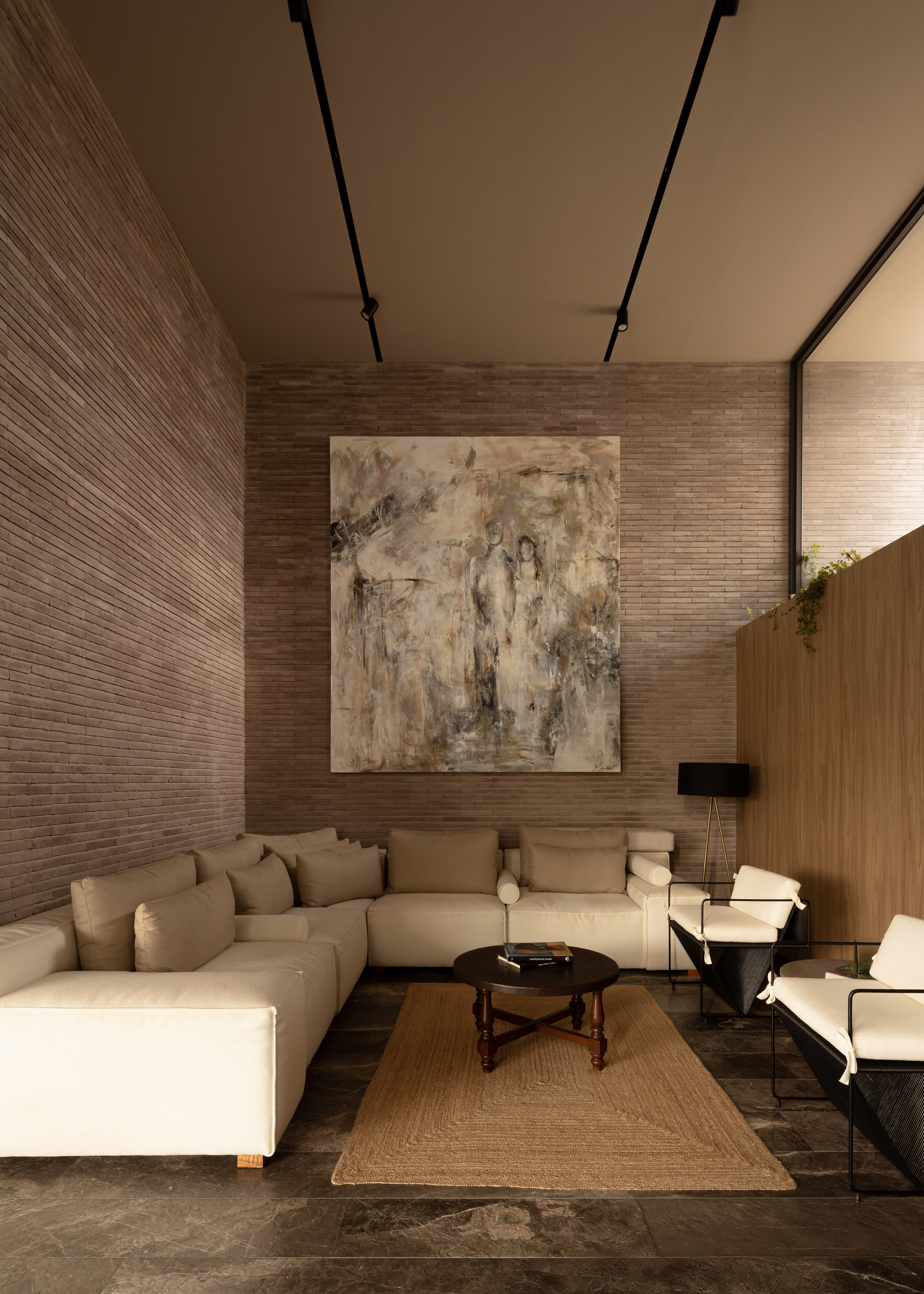 Double-height living room with horizontal brick walls and recessed ceiling track lighting