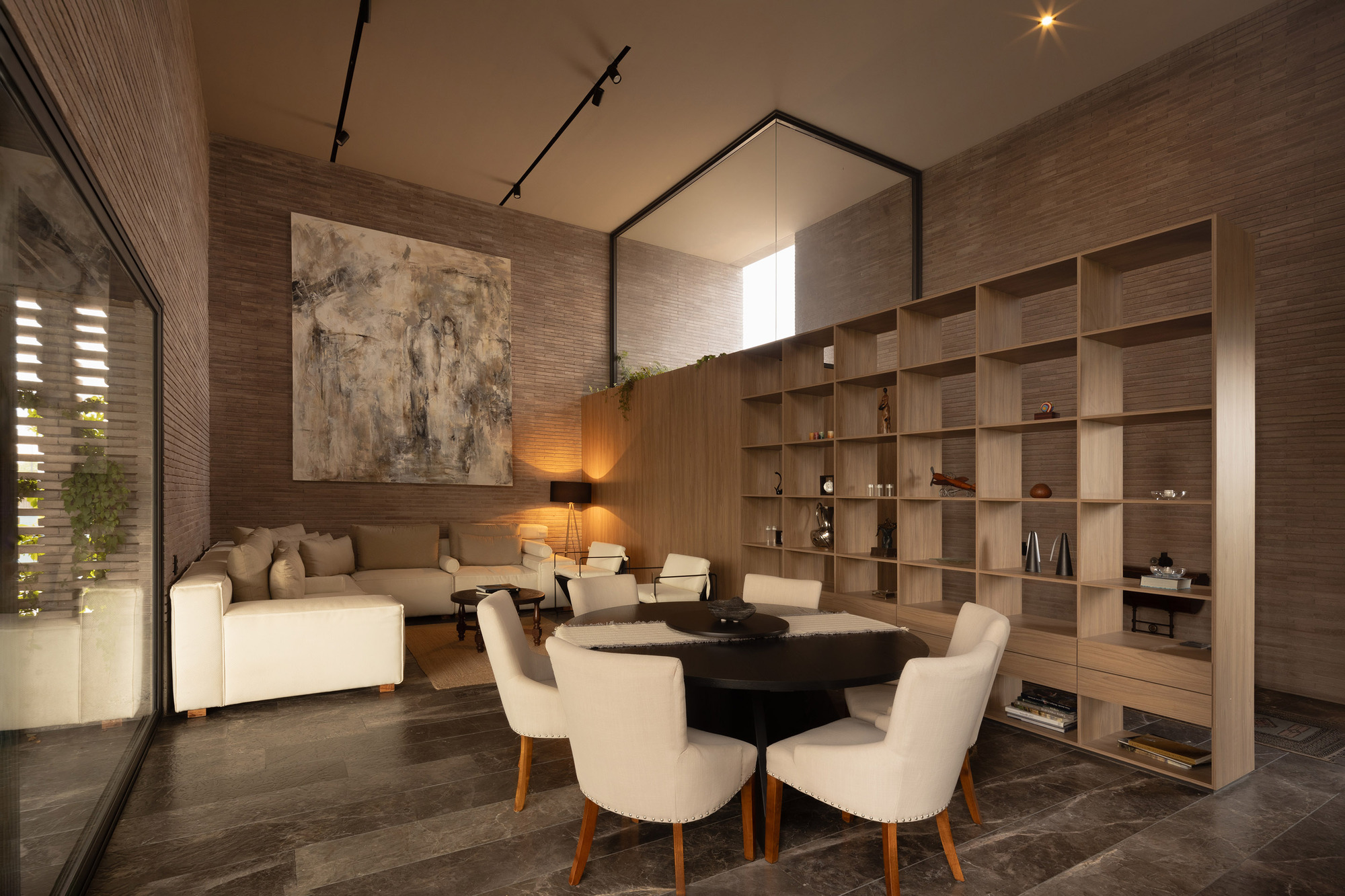 Double-height living room with horizontal timber wall cladding and built-in shelving beneath track lighting