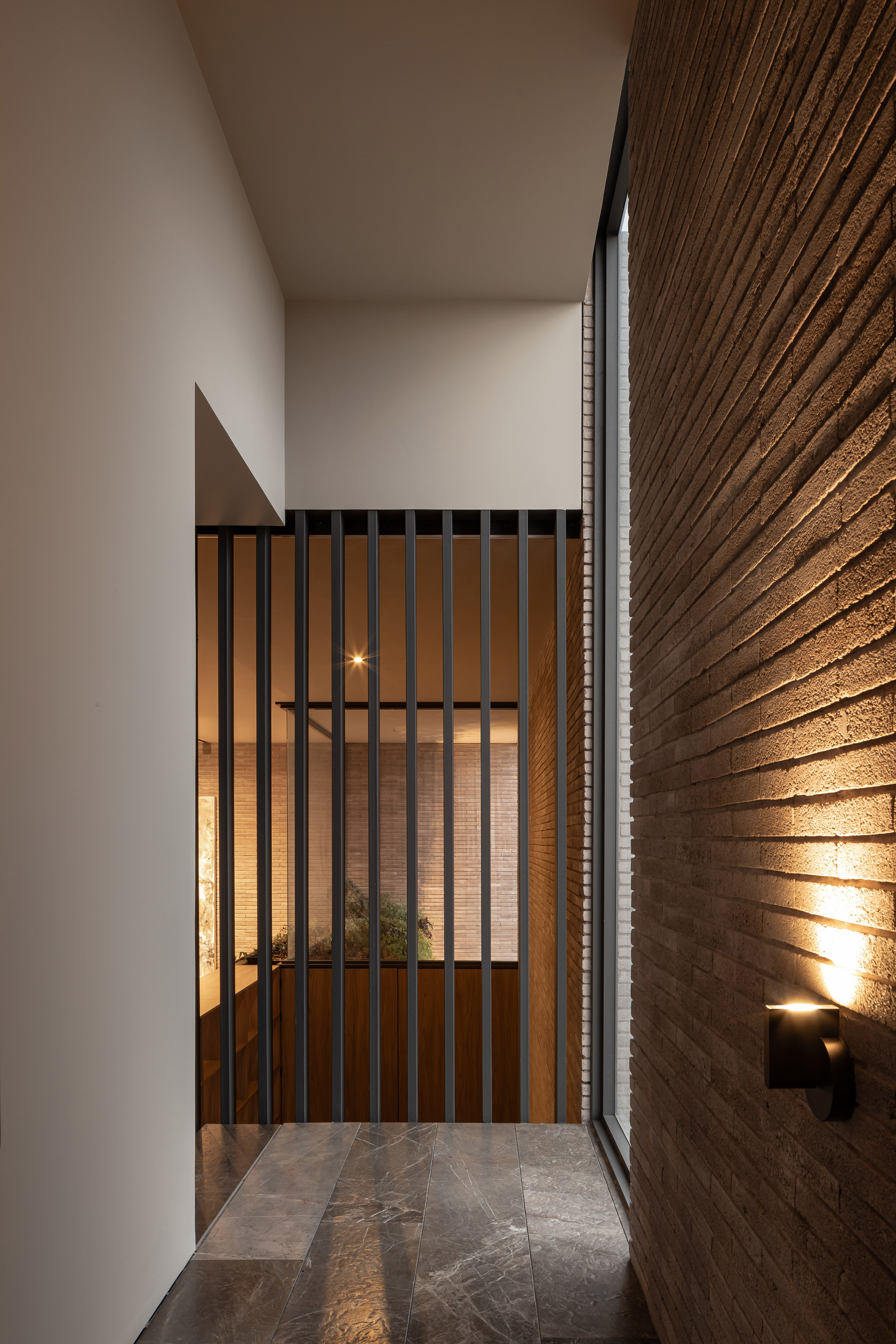 Entry vestibule with vertical timber screen door and grazing wall lights at twilight