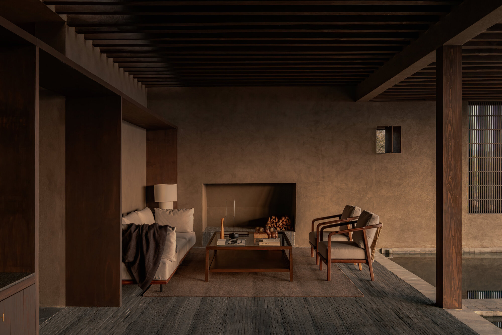 Sitting area with inset fireplace and timber-framed openings connecting to adjacent interior spaces