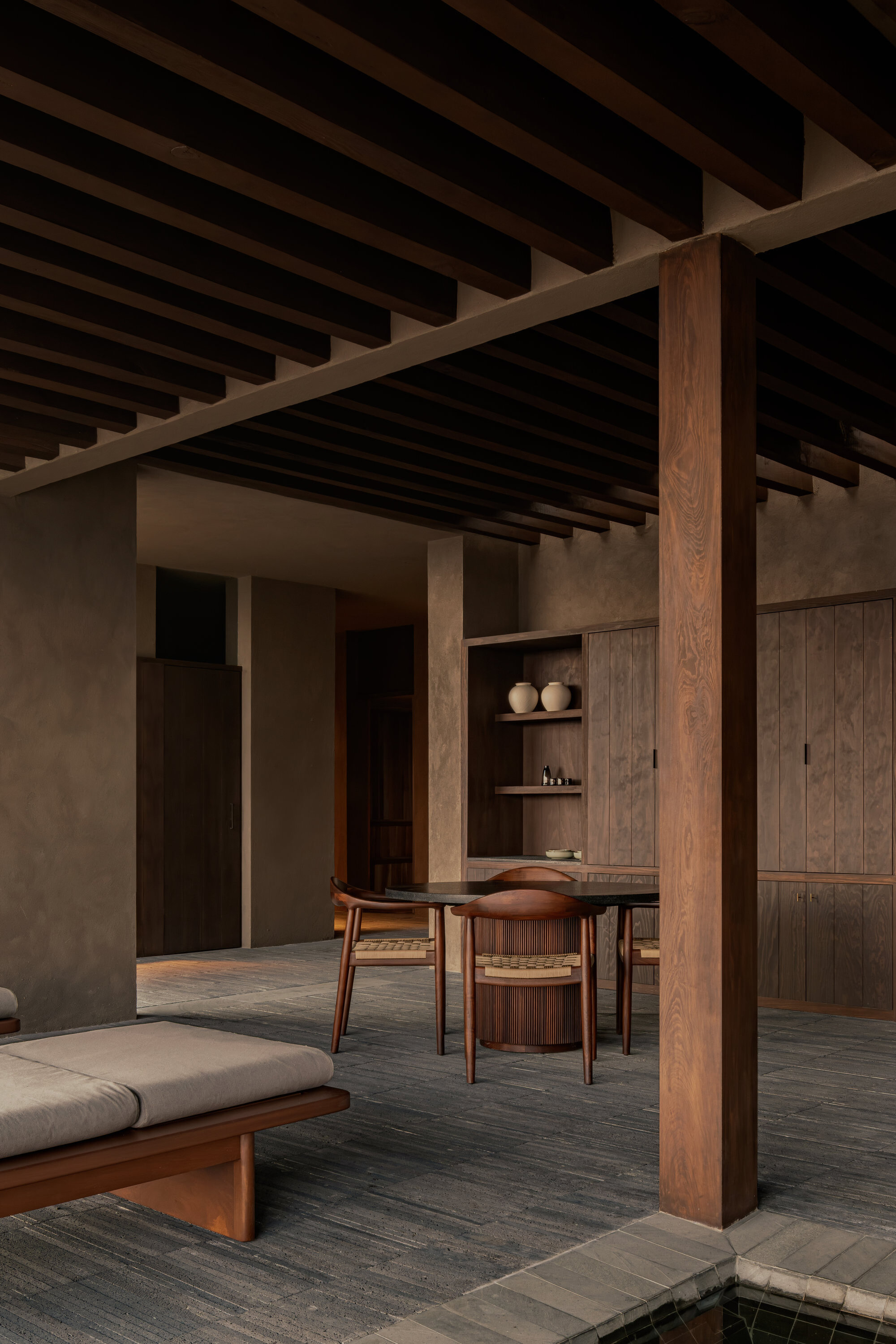 Open plan interior with timber columns defining dining and living zones under rhythmic ceiling joists