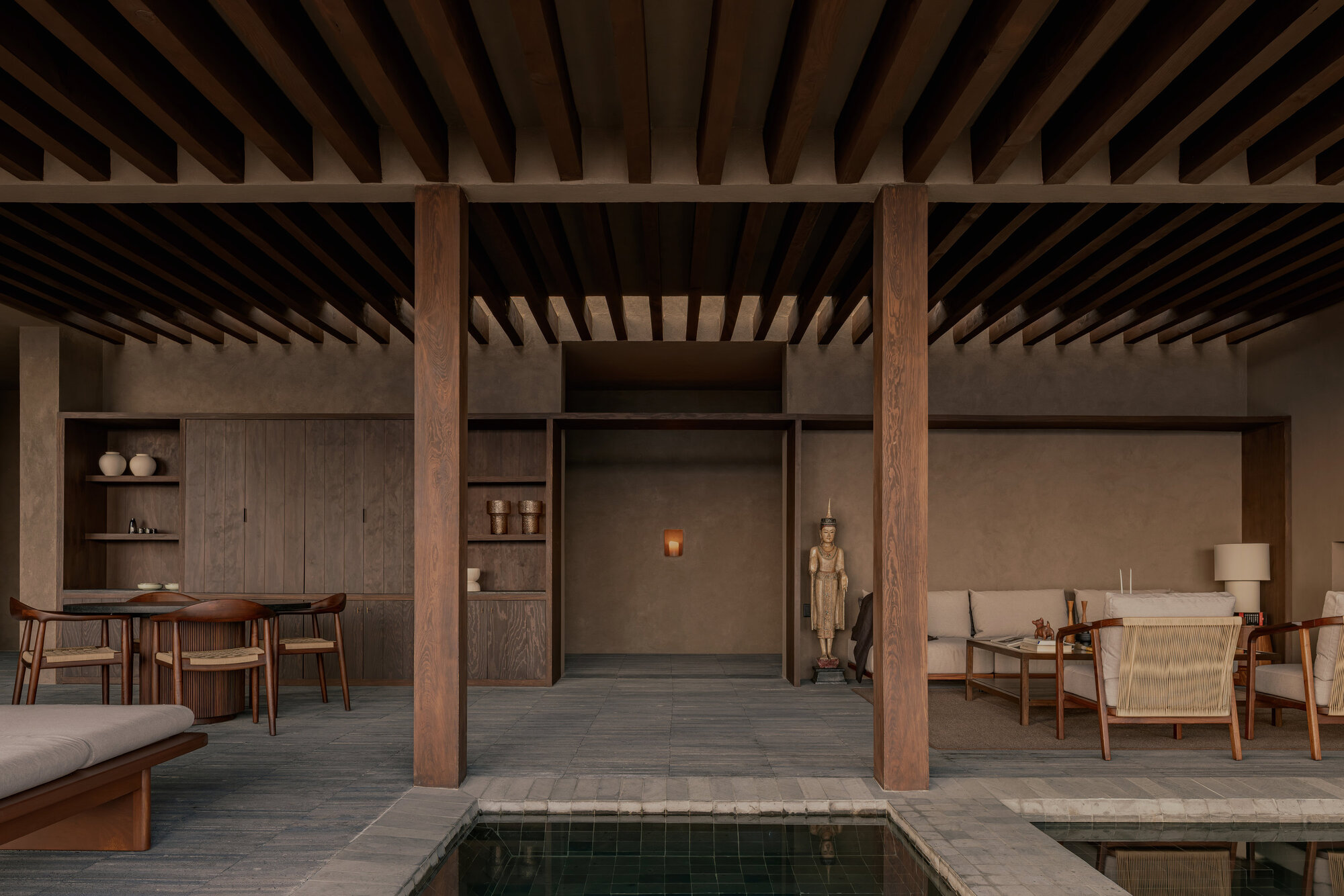 View across the interior pool toward shelving and a niche with sculpture flanked by timber columns