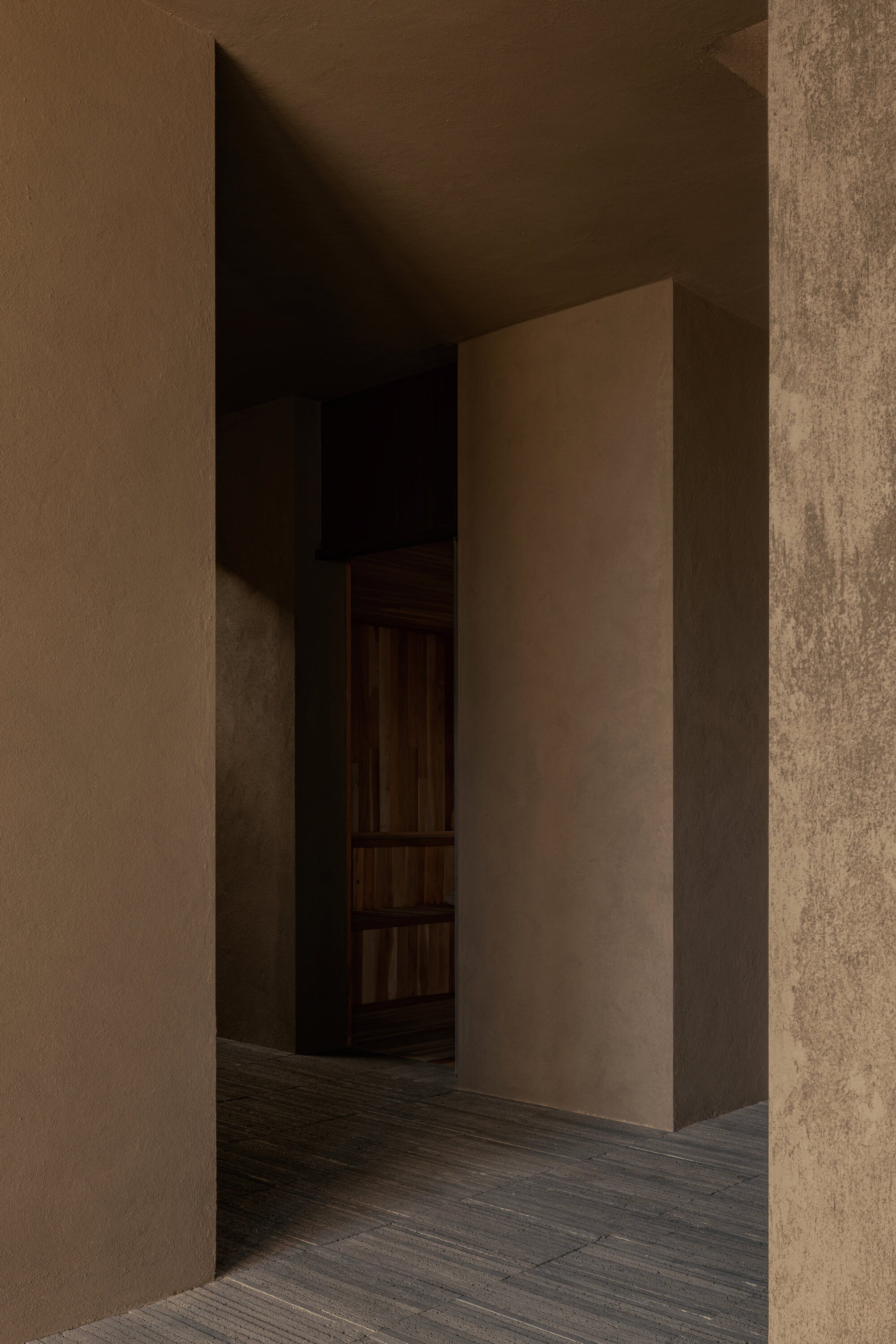 Narrow corridor with textured plaster walls and a freestanding partition in warm ambient light
