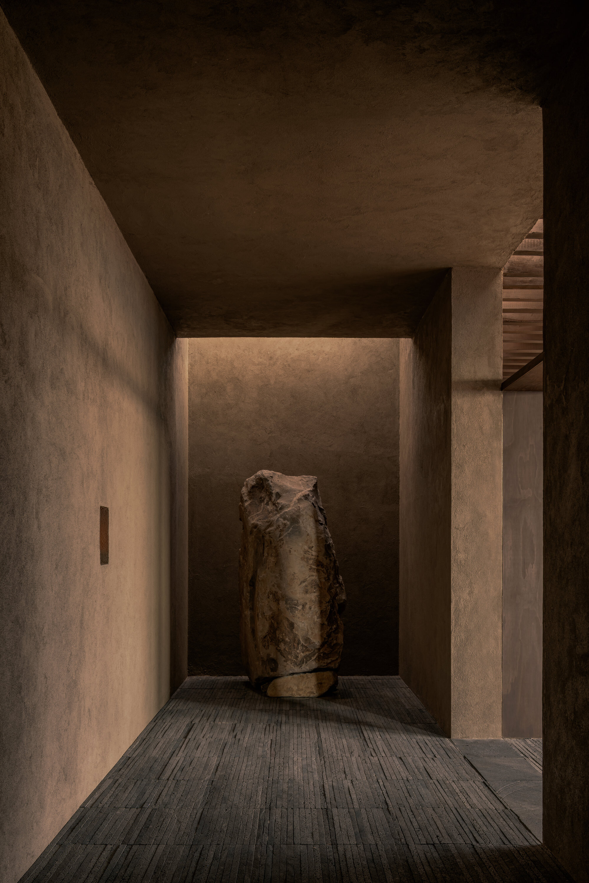 Recessed alcove with backlit wall displaying a weathered ceramic vessel on timber decking