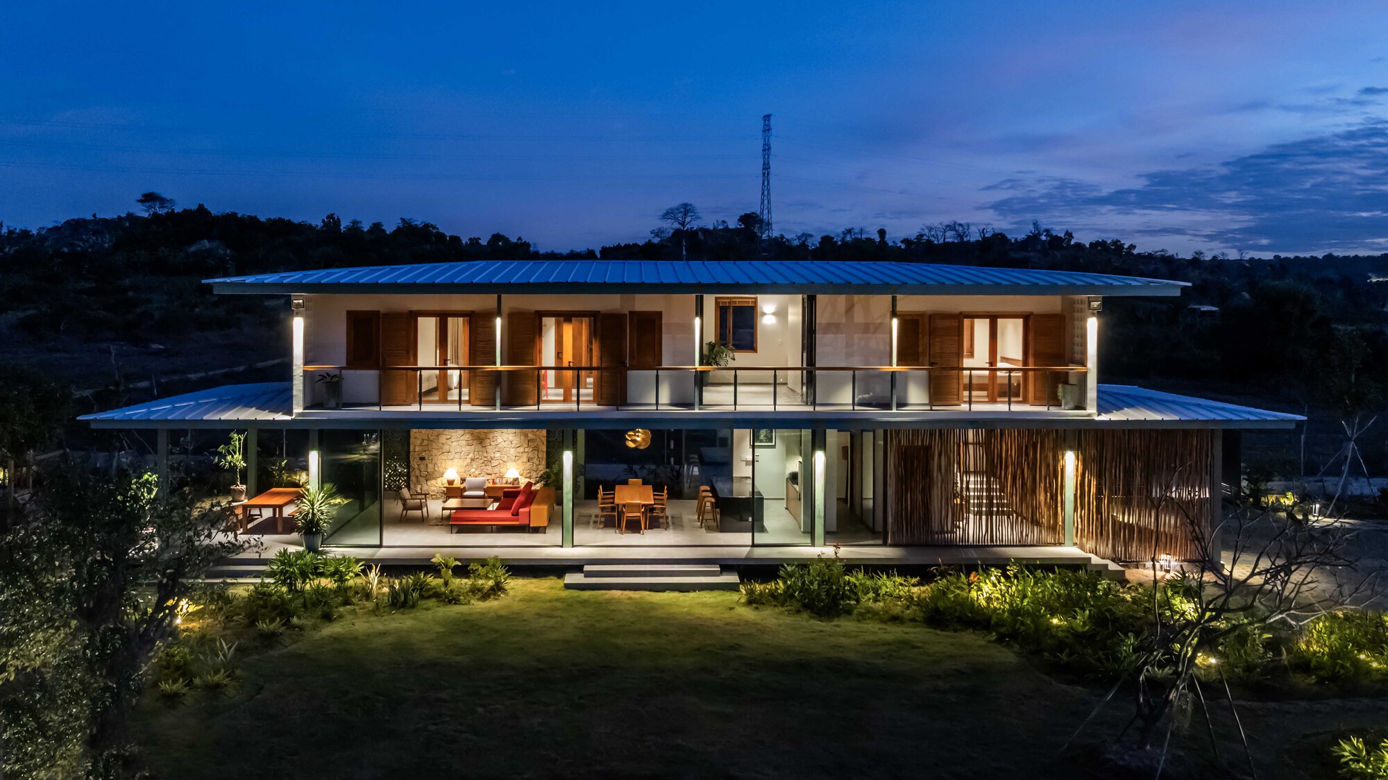 Night view of the illuminated facade with reflecting roof and shadows cast across the lawn
