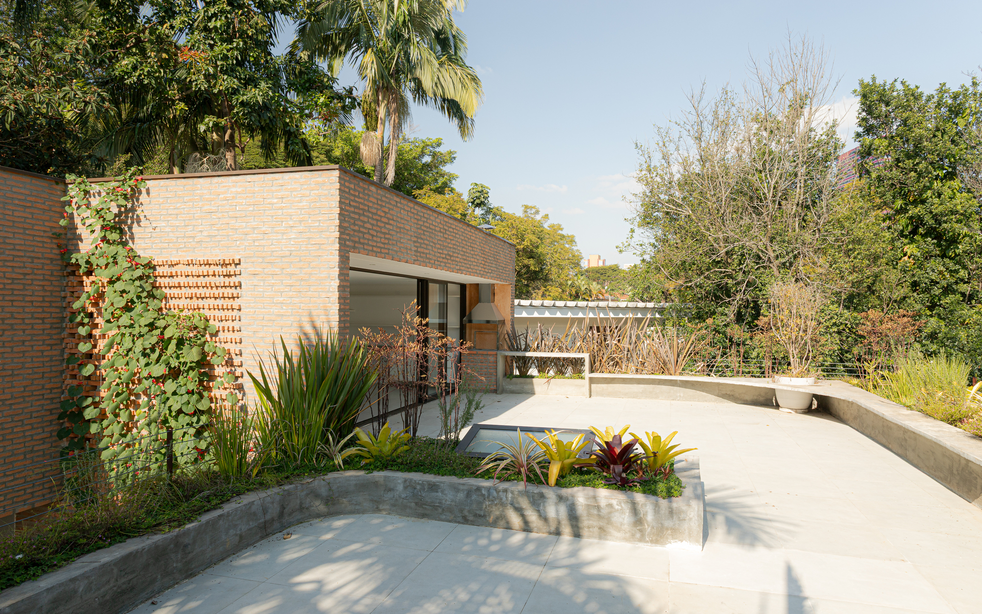 Exterior terrace with curved concrete planters and brick walls beneath a pergola structure