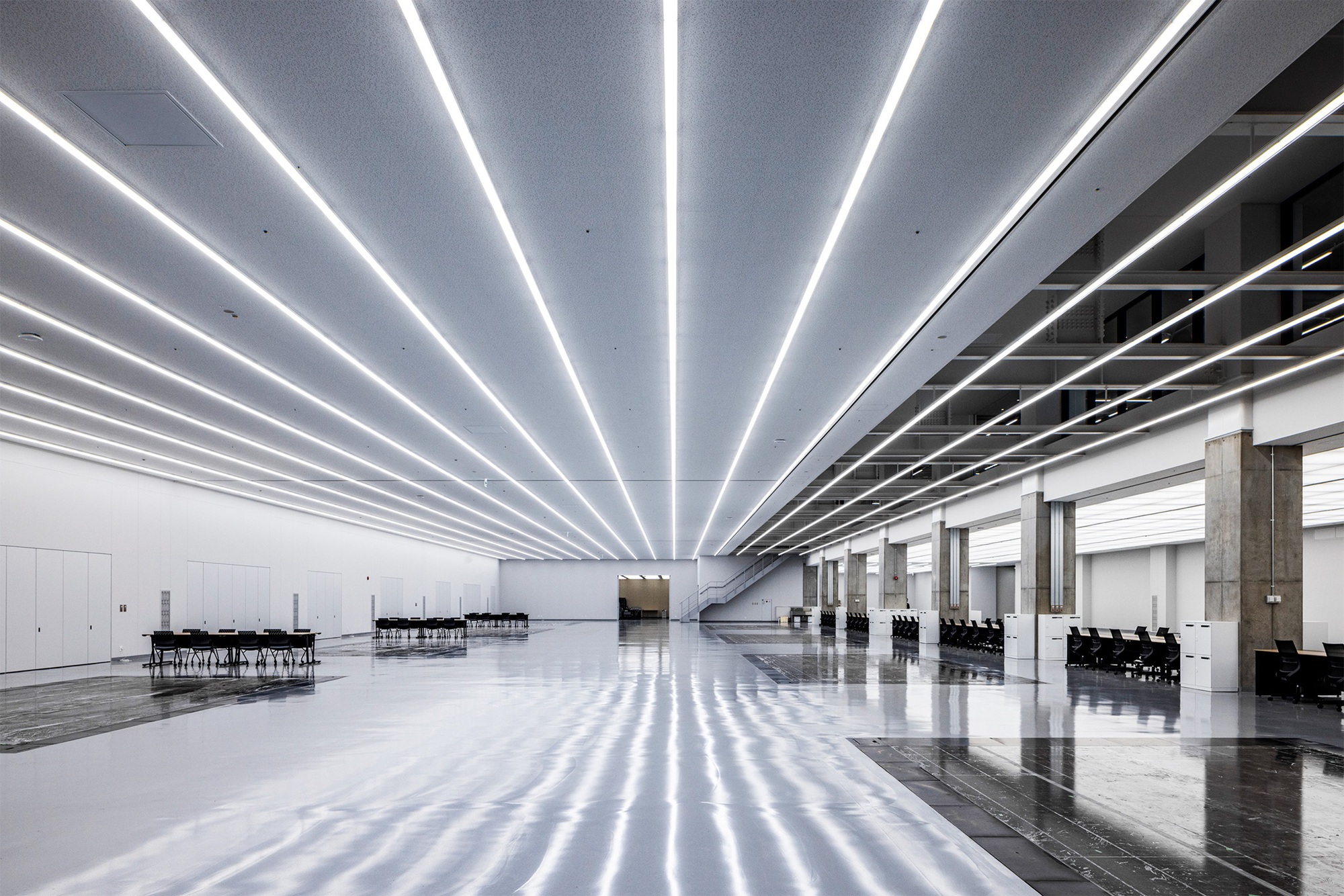 Expansive interior hall with parallel LED light strips radiating across the polished floor and ceiling
