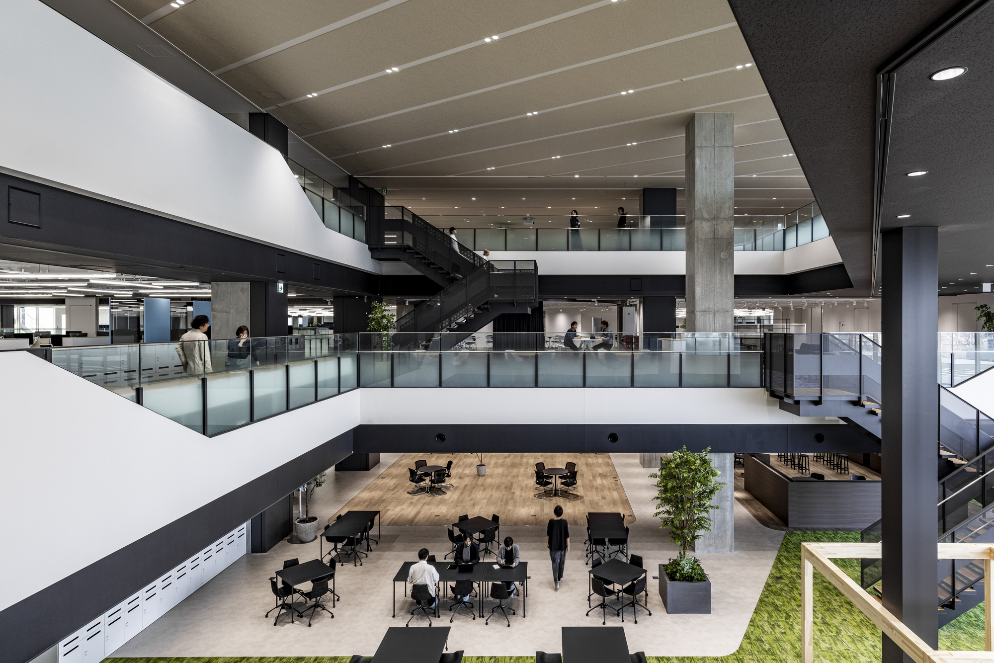 View down into a multi-story atrium with glass guardrails and a person walking below