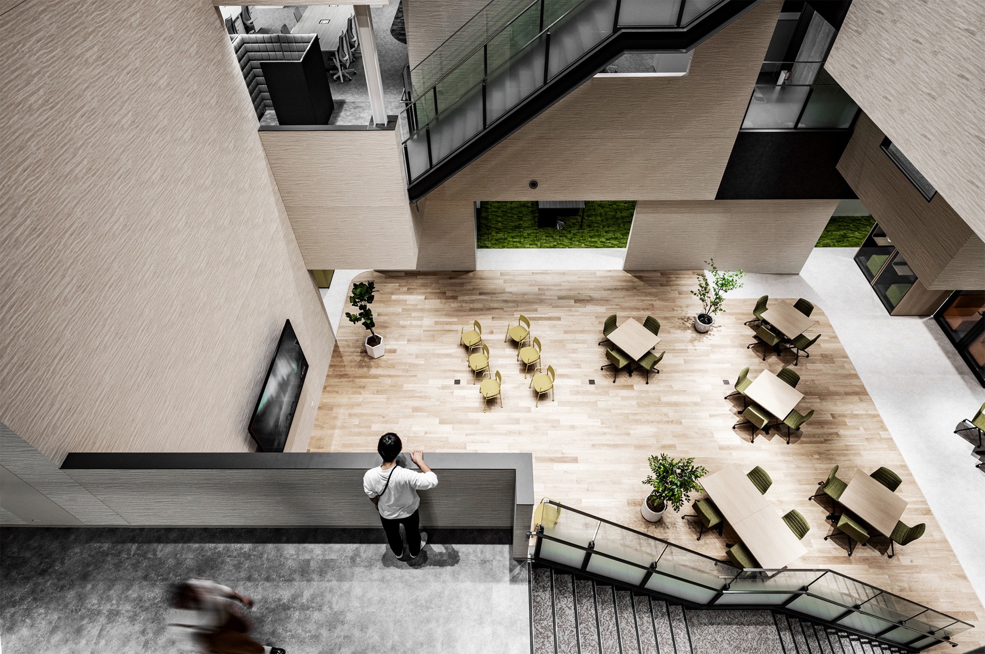 Top-down view of an atrium floor with workers at scattered tables beside a concrete column