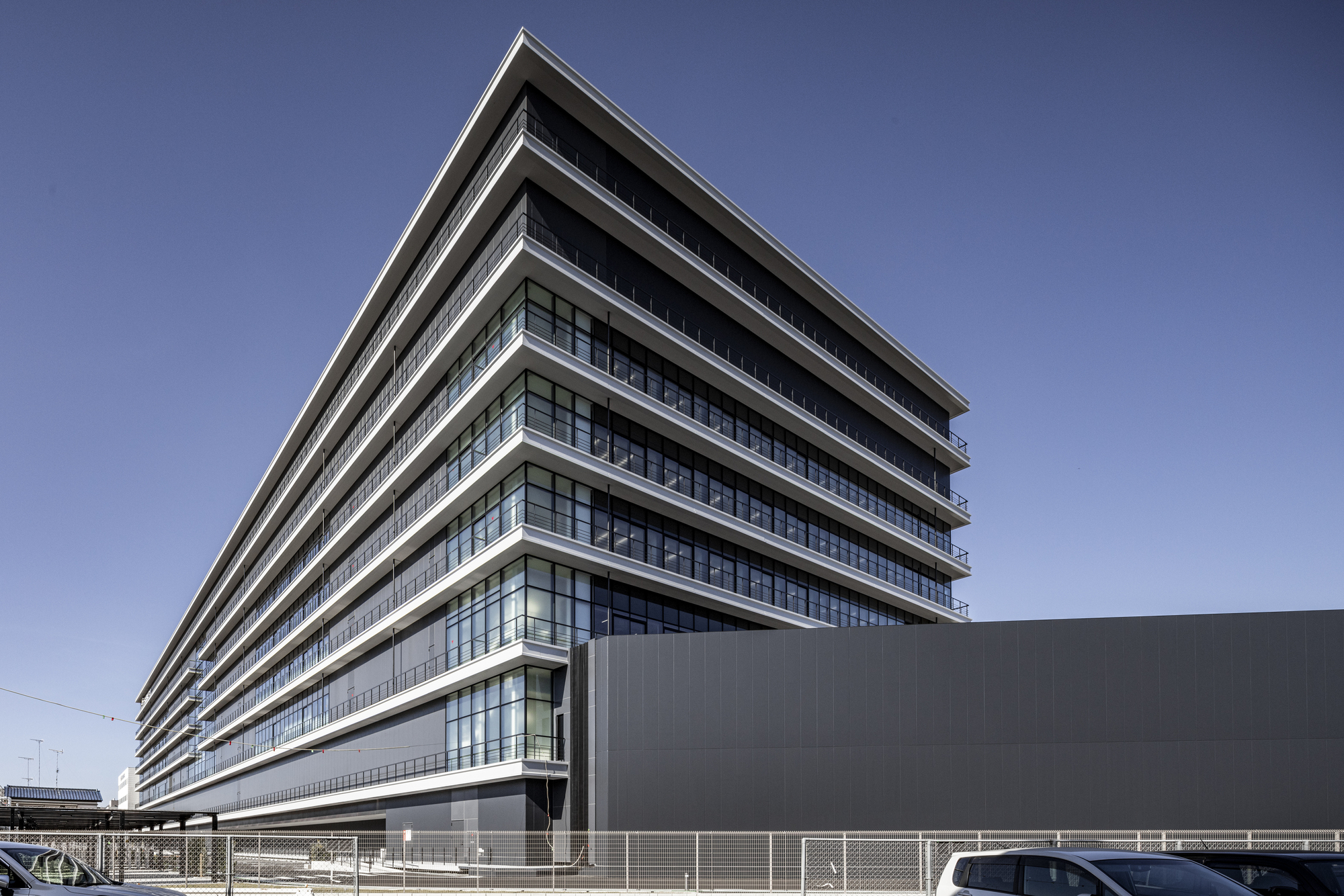 Side elevation showing layered floor plates with continuous balconies and metal screening below