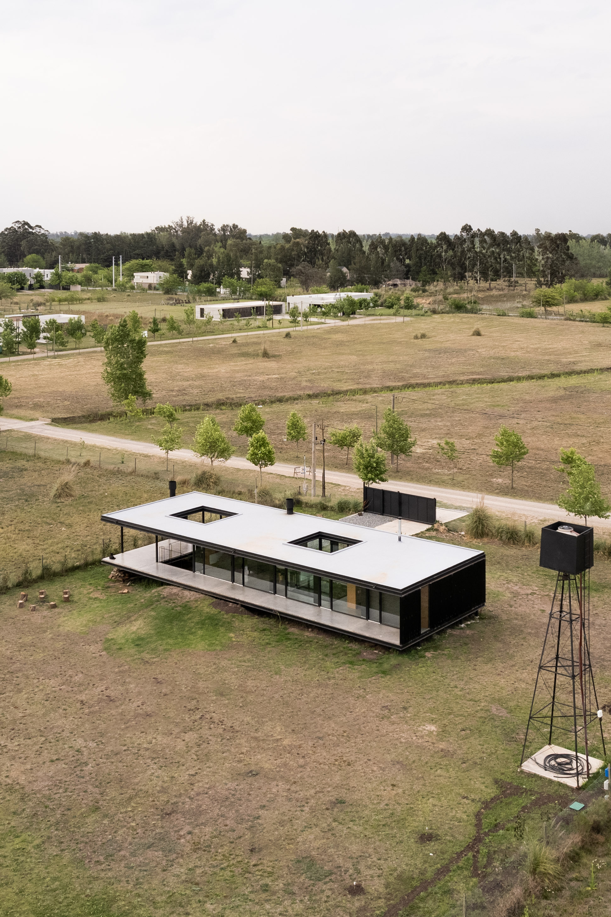 Aerial view of the elevated white-roofed pavilion with two courtyards in an open grassland with water tower