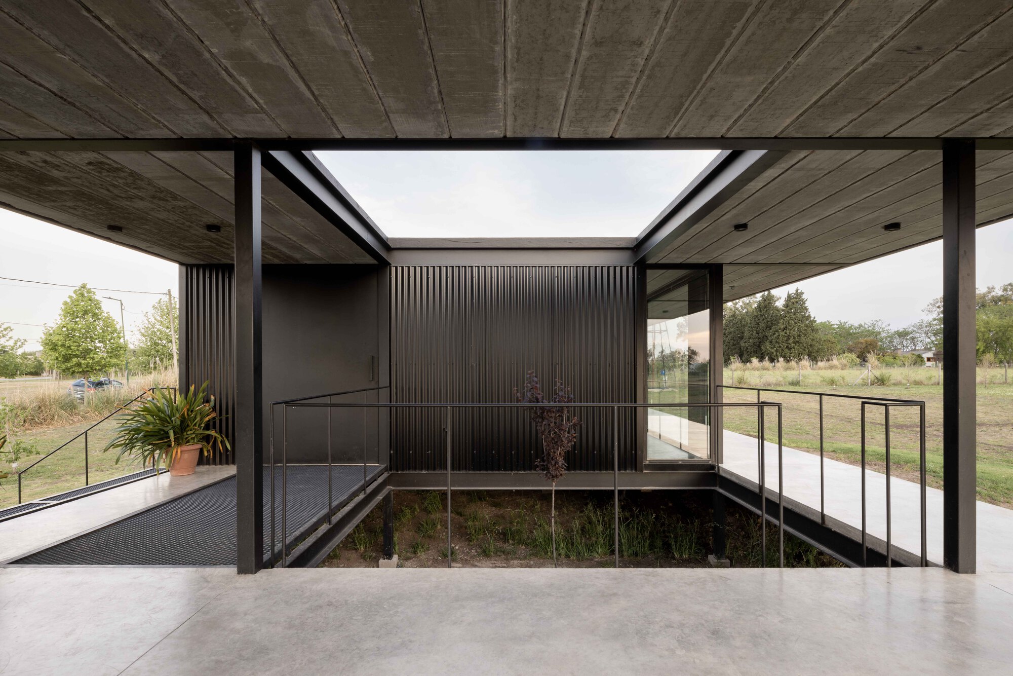 Interior courtyard framed by timber soffit and corrugated metal walls with planted bed below