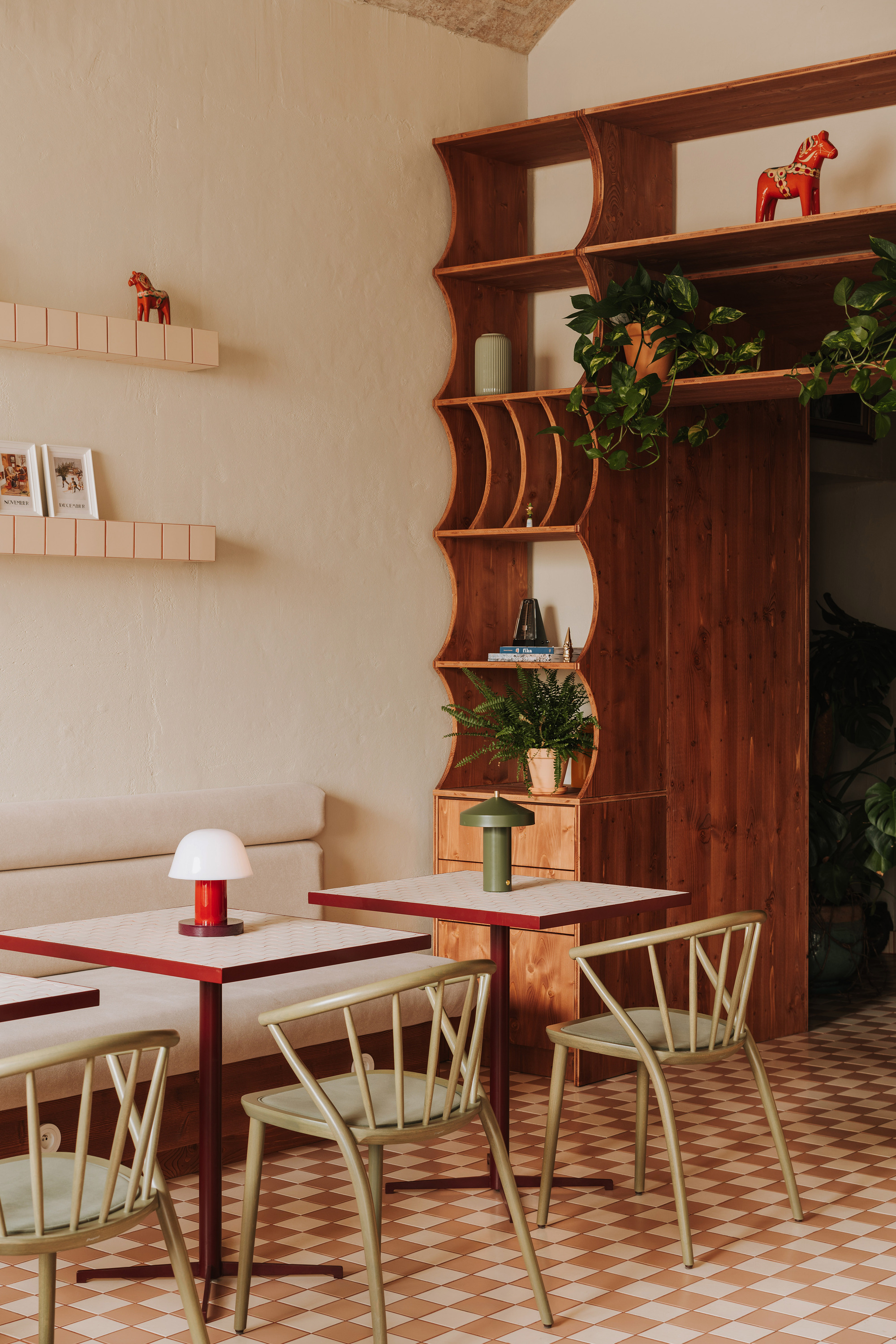 Dining tables with curved timber shelving displaying potted plants and drawers beneath the shelves