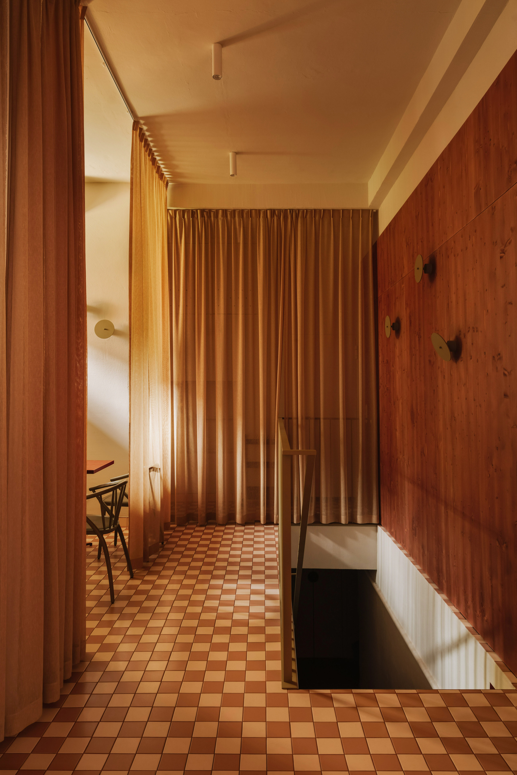 Corridor with floor-to-ceiling curtain divider and checkered tile floor in warm afternoon light