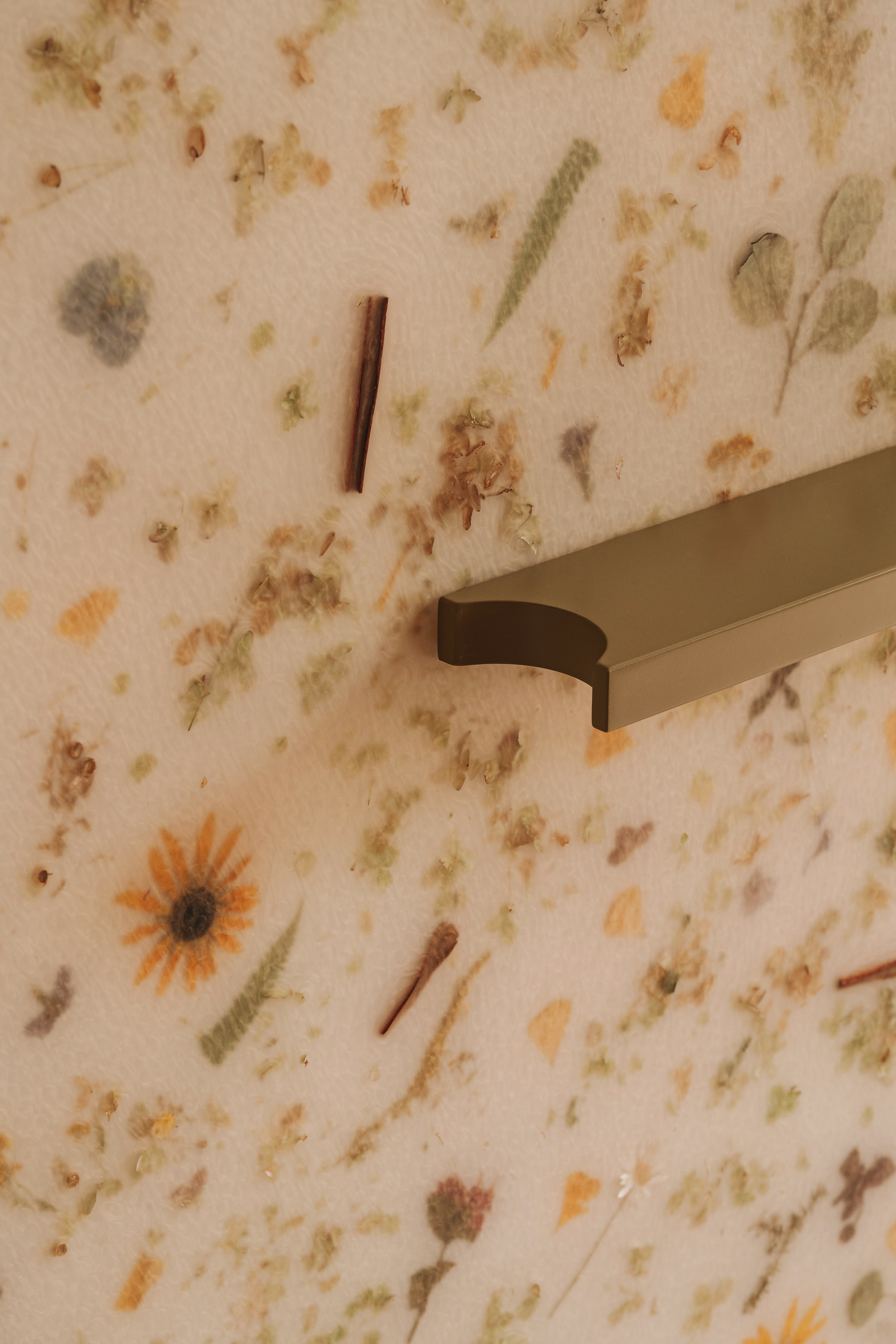 Door handle mounted on panel embedded with pressed flowers and plant material