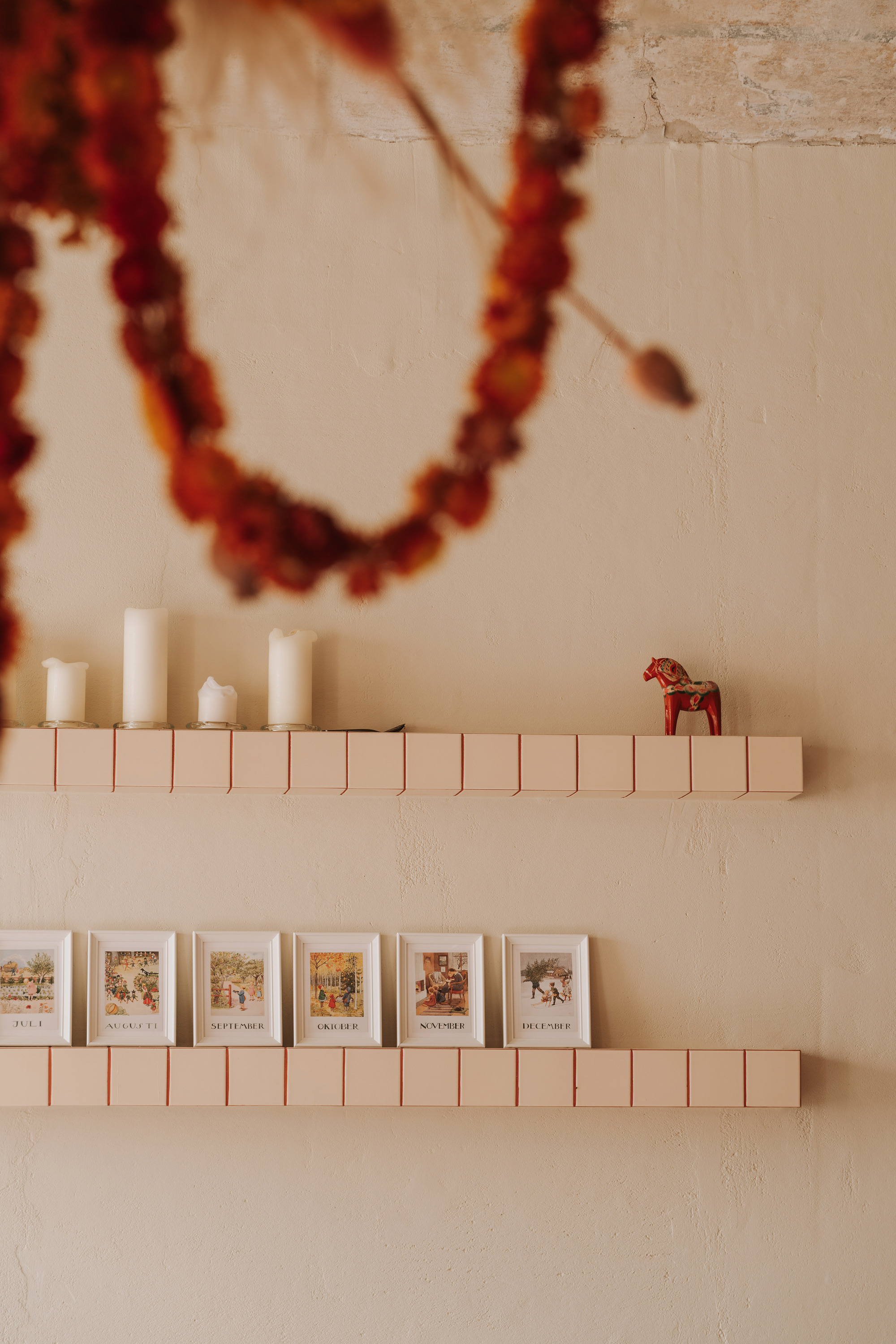 Wall-mounted shelves constructed from rectangular tiles displaying candles and printed cards