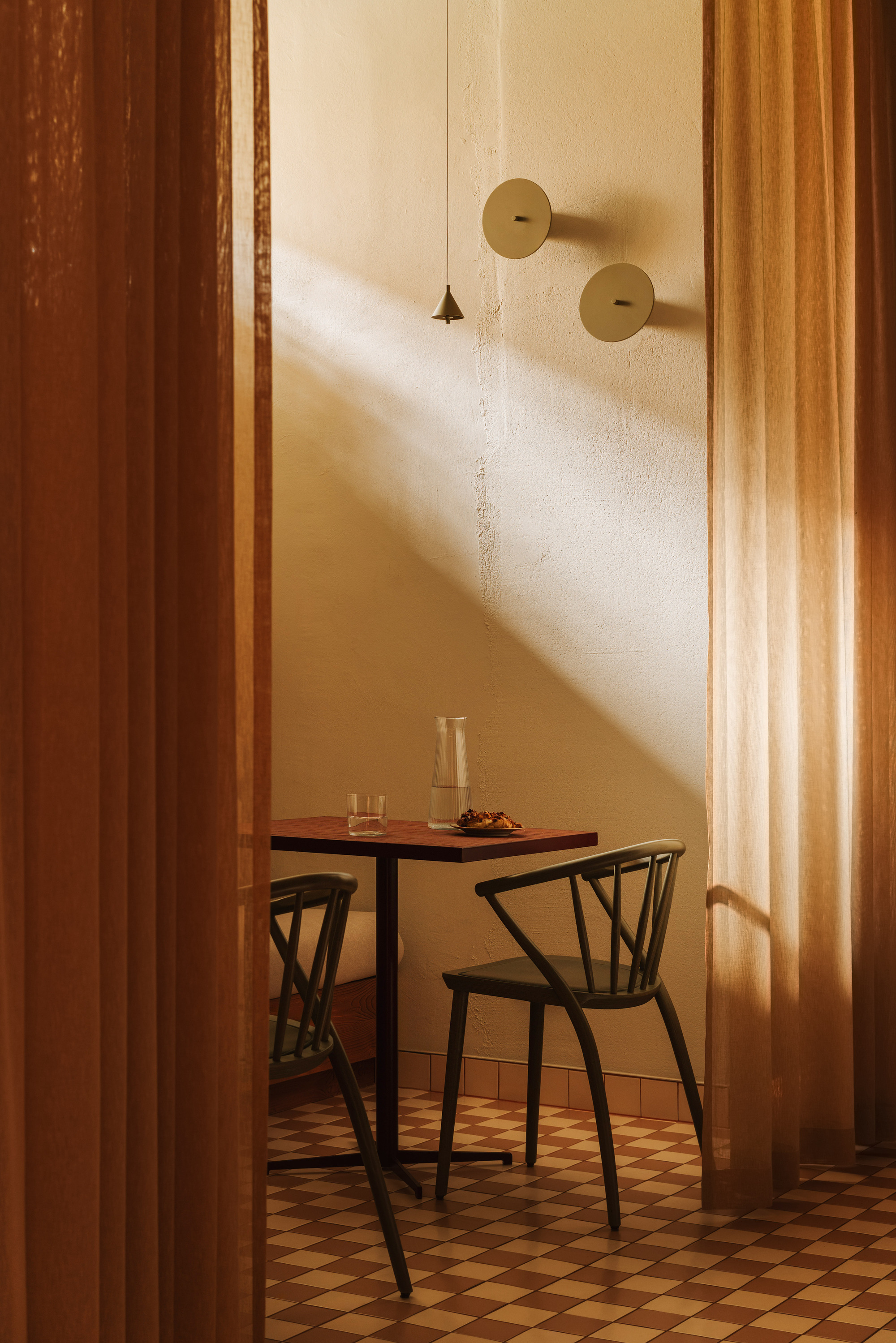 Small dining table with two chairs framed by timber doorway in soft afternoon sunlight