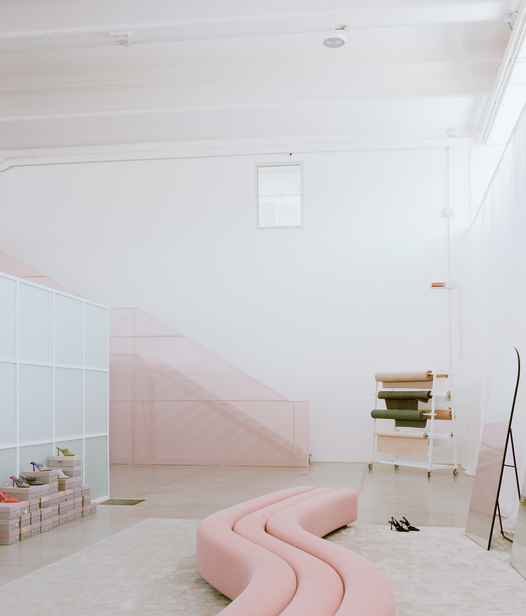 Light-filled room with pale pink staircase and curved pink seating beneath white timber ceiling
