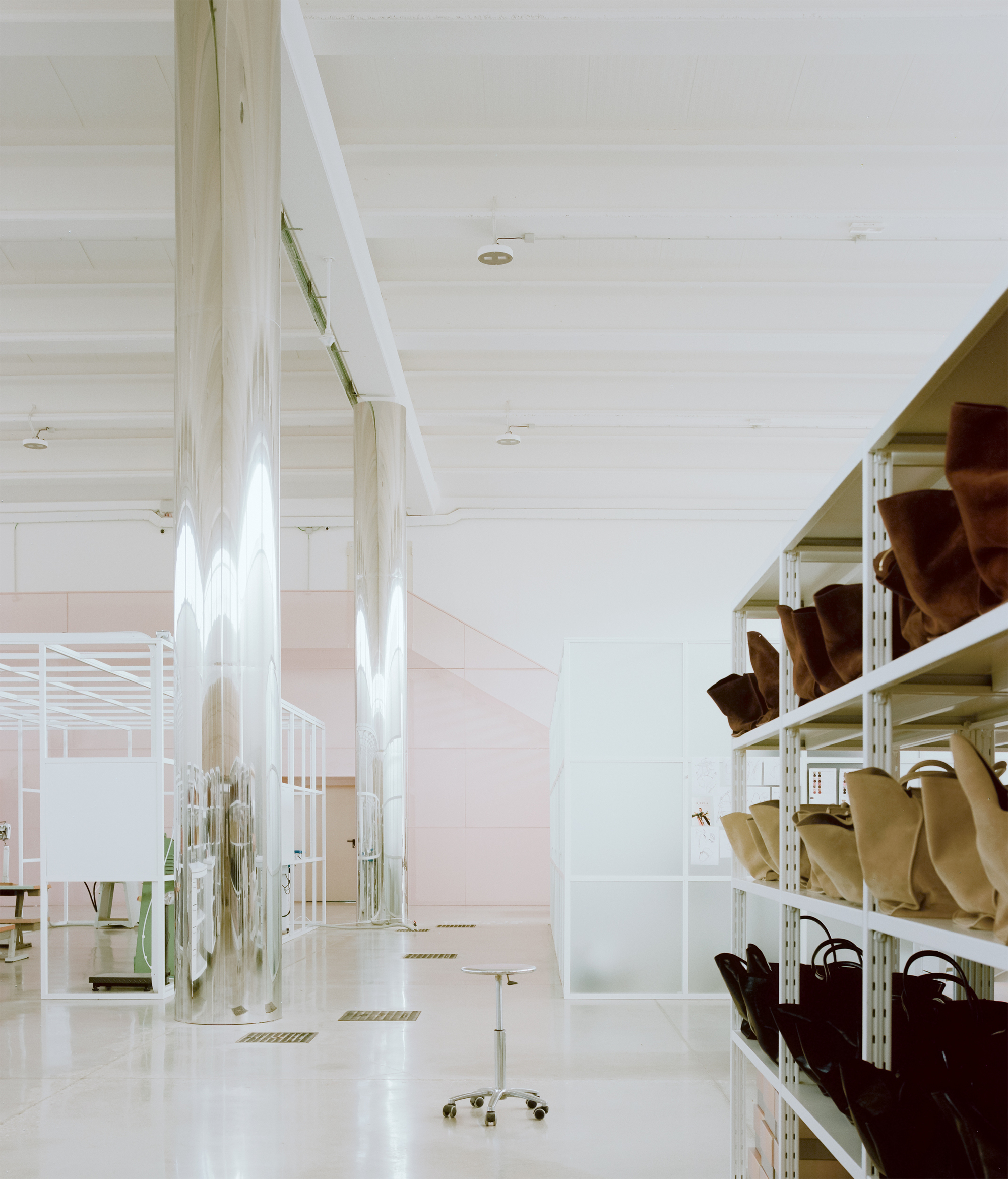 White metal shelving displaying footwear and accessories beneath exposed timber beams