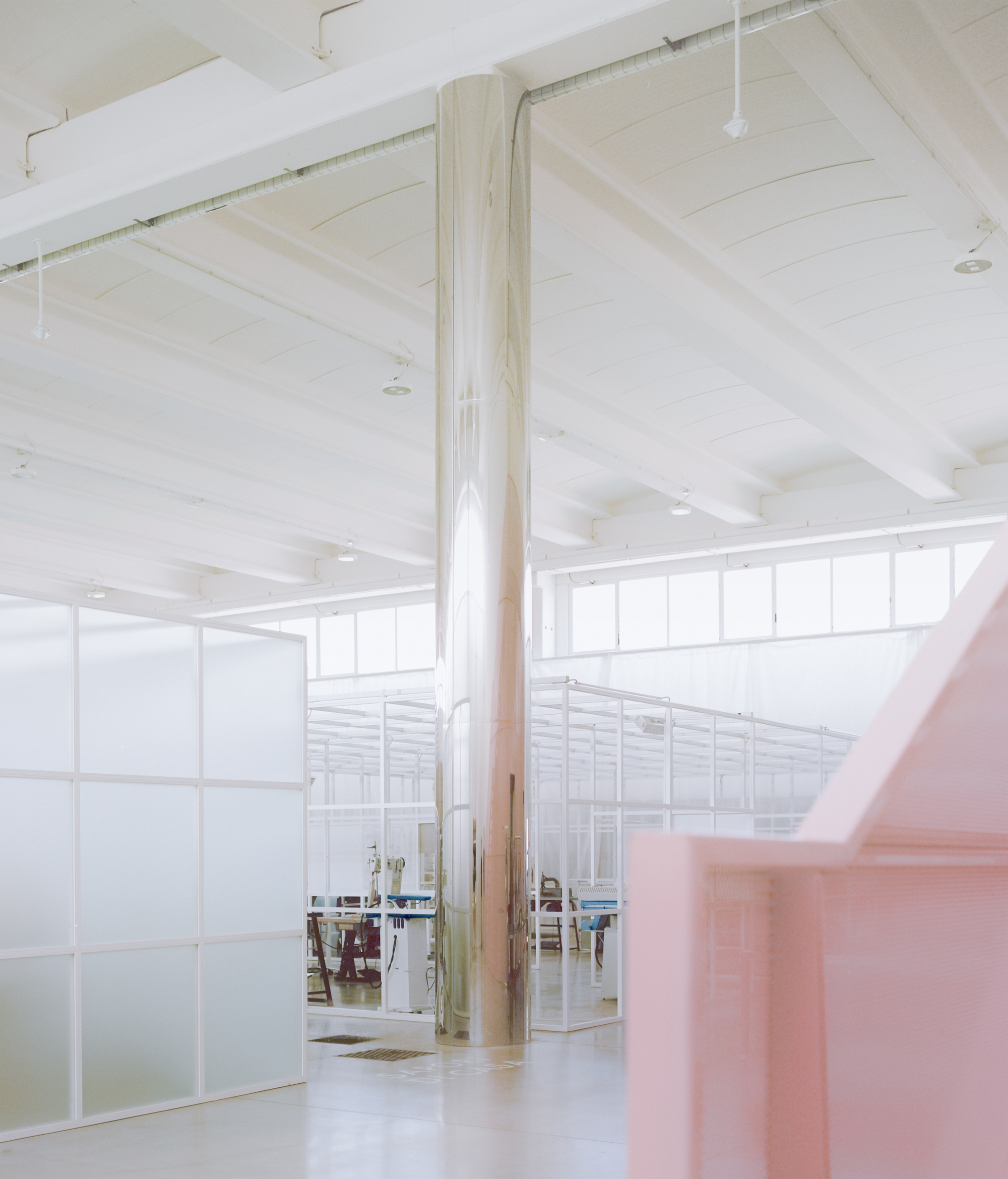 Interior with translucent glass partition wall, timber column, and whitewashed ceiling beams above polished floor