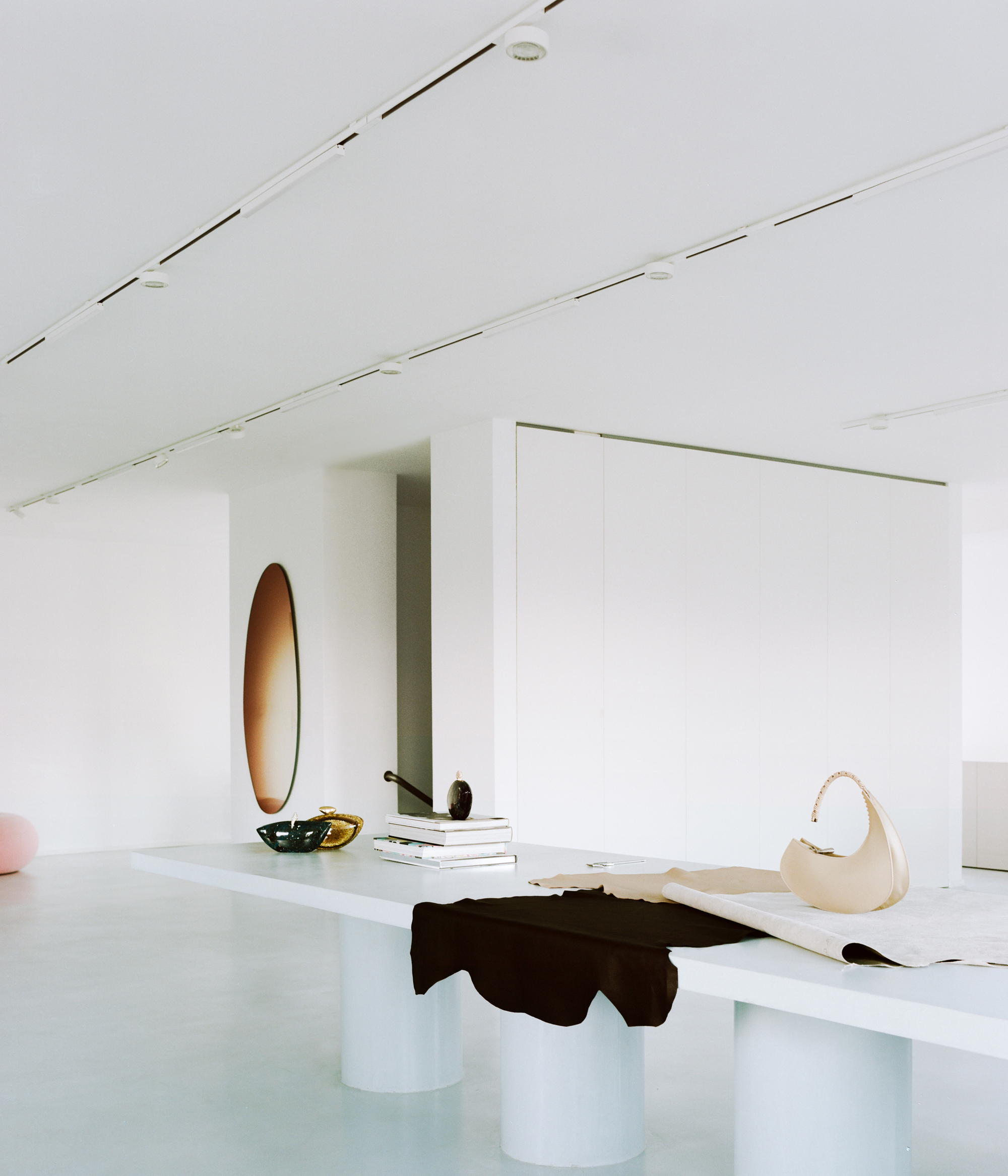 White display counter with cylindrical pedestal base holding folded garments and accessories near a recessed doorway