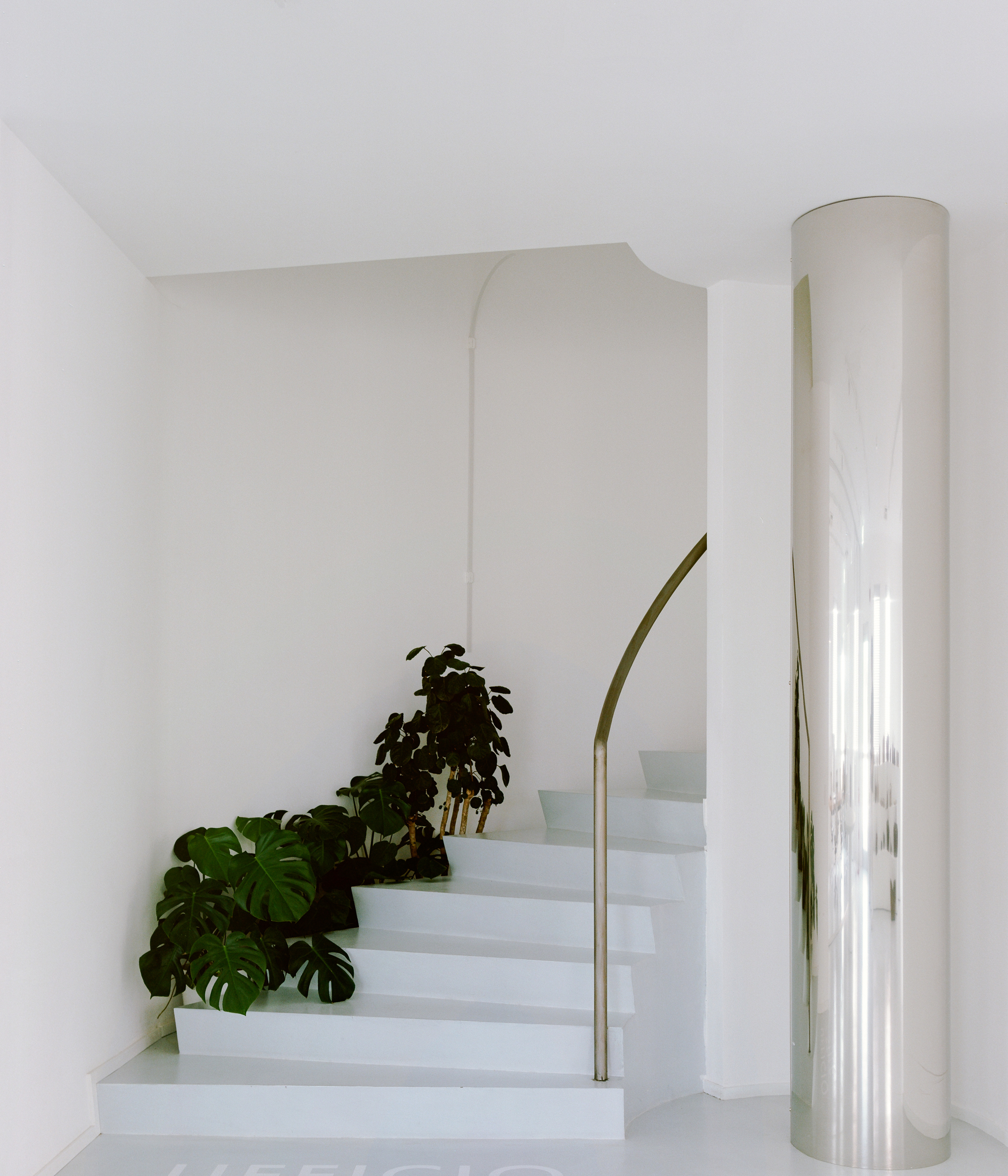 White interior staircase with curved handrail and potted plants beside the steps