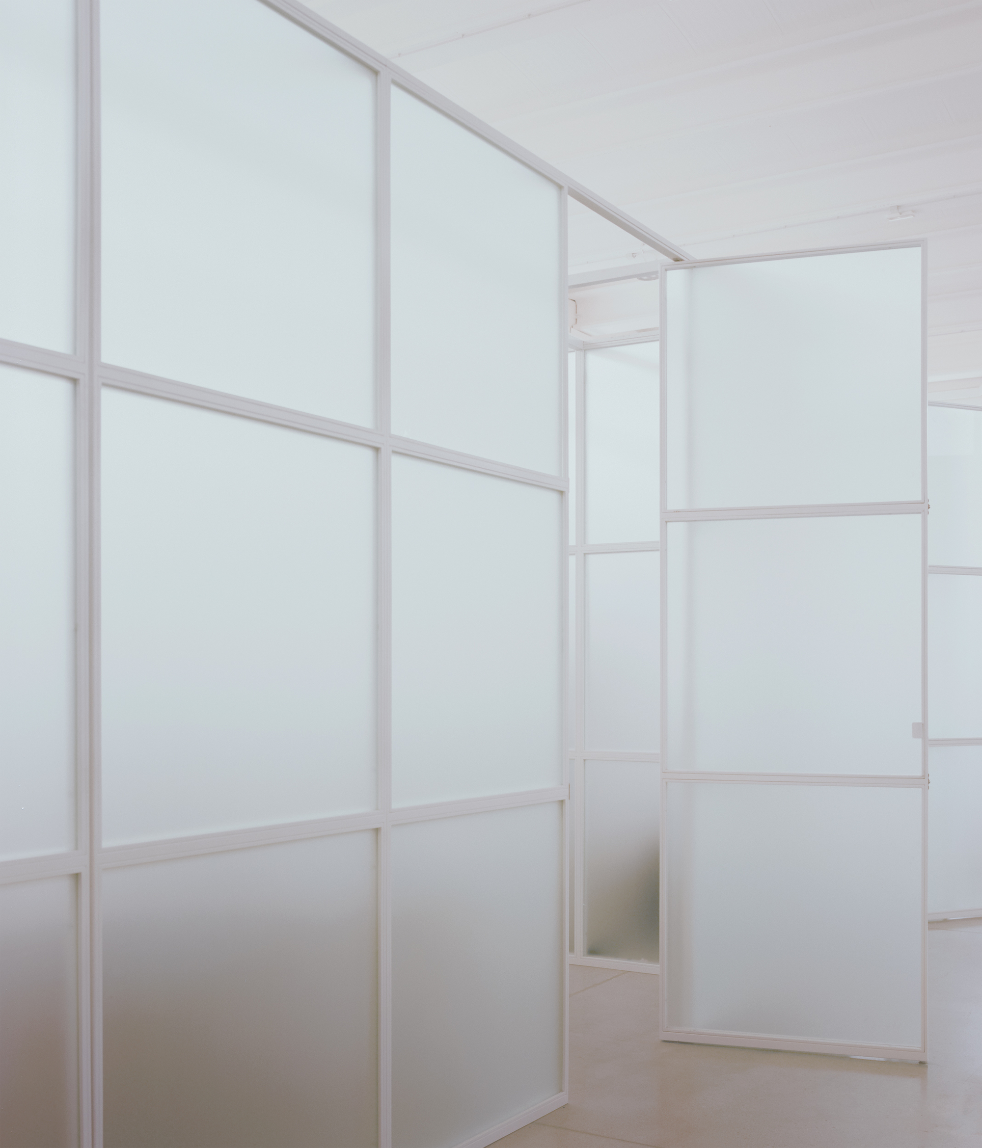 Interior room with translucent white partitions framed in pale wood under diffused natural light