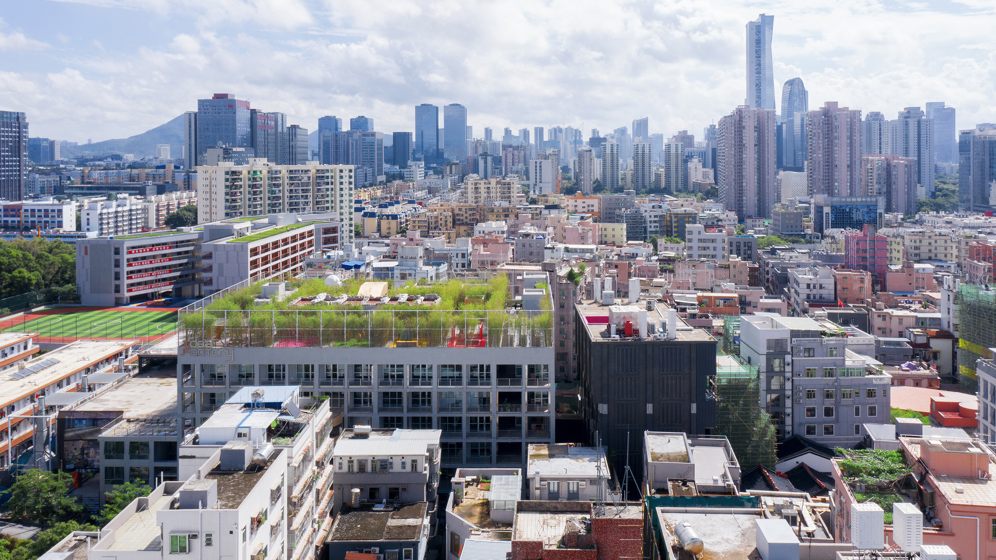 Elevated view of multiple rooftop sports fields with running tracks amid low-rise buildings and distant towers