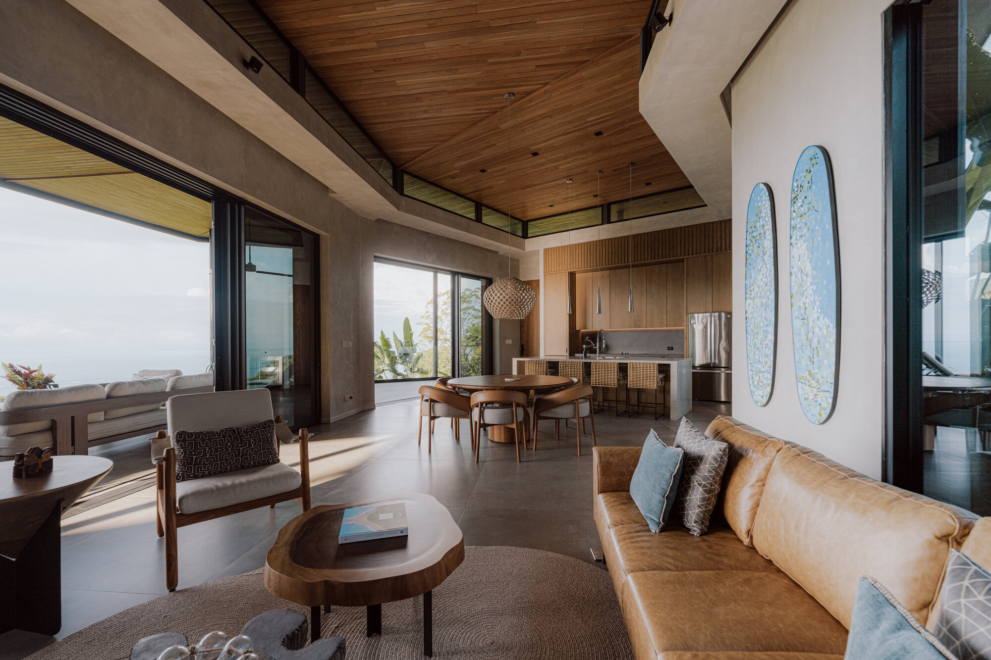 Open-plan living space with timber ceiling, concrete beams, and surfboards mounted on the wall