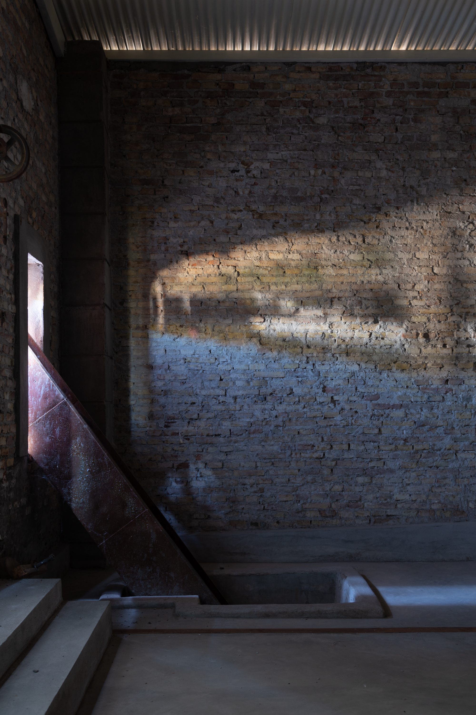 Interior staircase with steel handrail and exposed brick wall illuminated by natural light