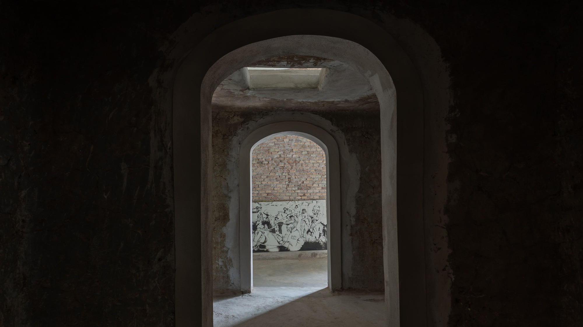 Sequence of arched brick doorways leading through dimly lit vaulted interior spaces